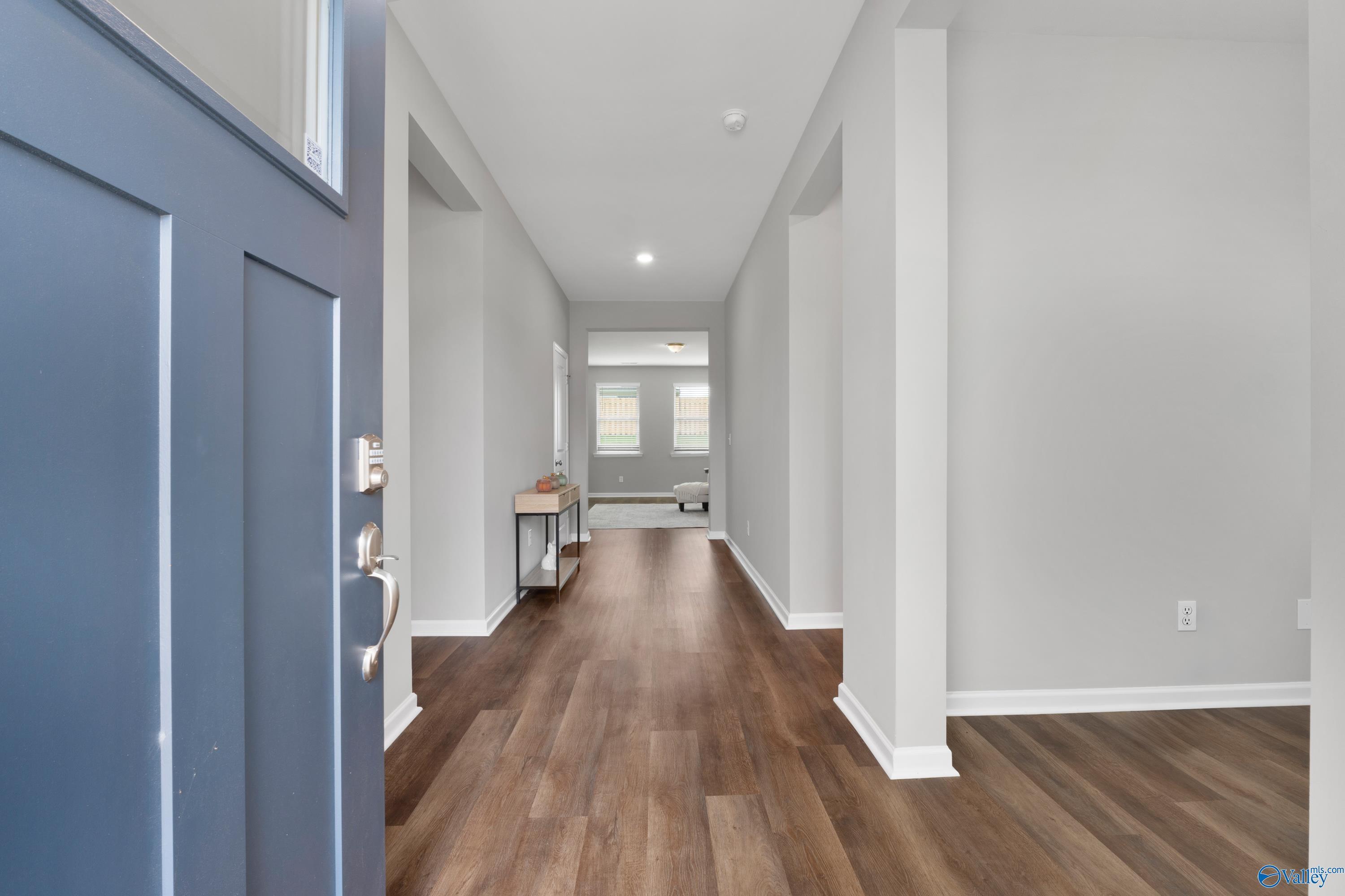Welcoming entry hallway with hardwood floors, gray walls, and columns in The Noble 3-bedroom home, Madison, Alabama