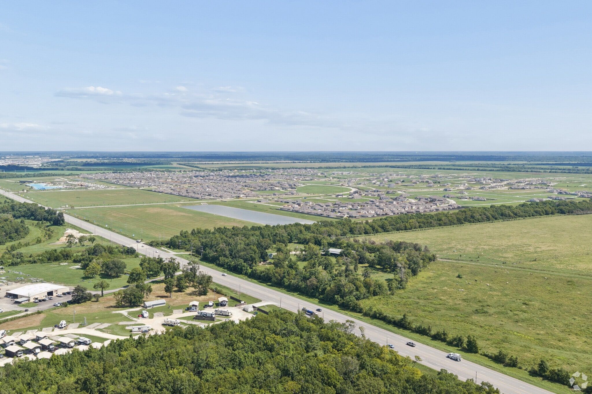 Aerial view of sprawling master-planned community in Dayton, Texas with new homes, open fields, and highway access nearby