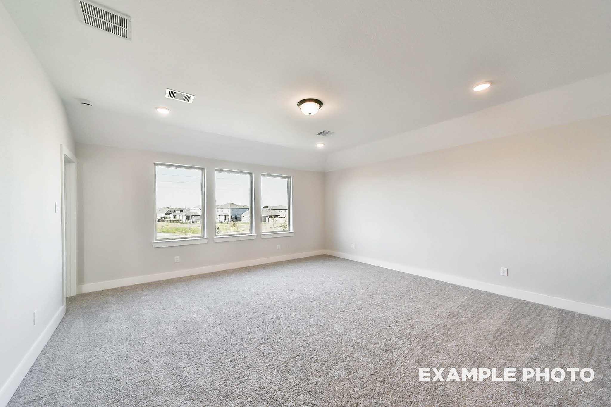 Spacious empty bedroom with large windows overlooking fields in Davidson Homes The Philip C, Rosharon, Texas