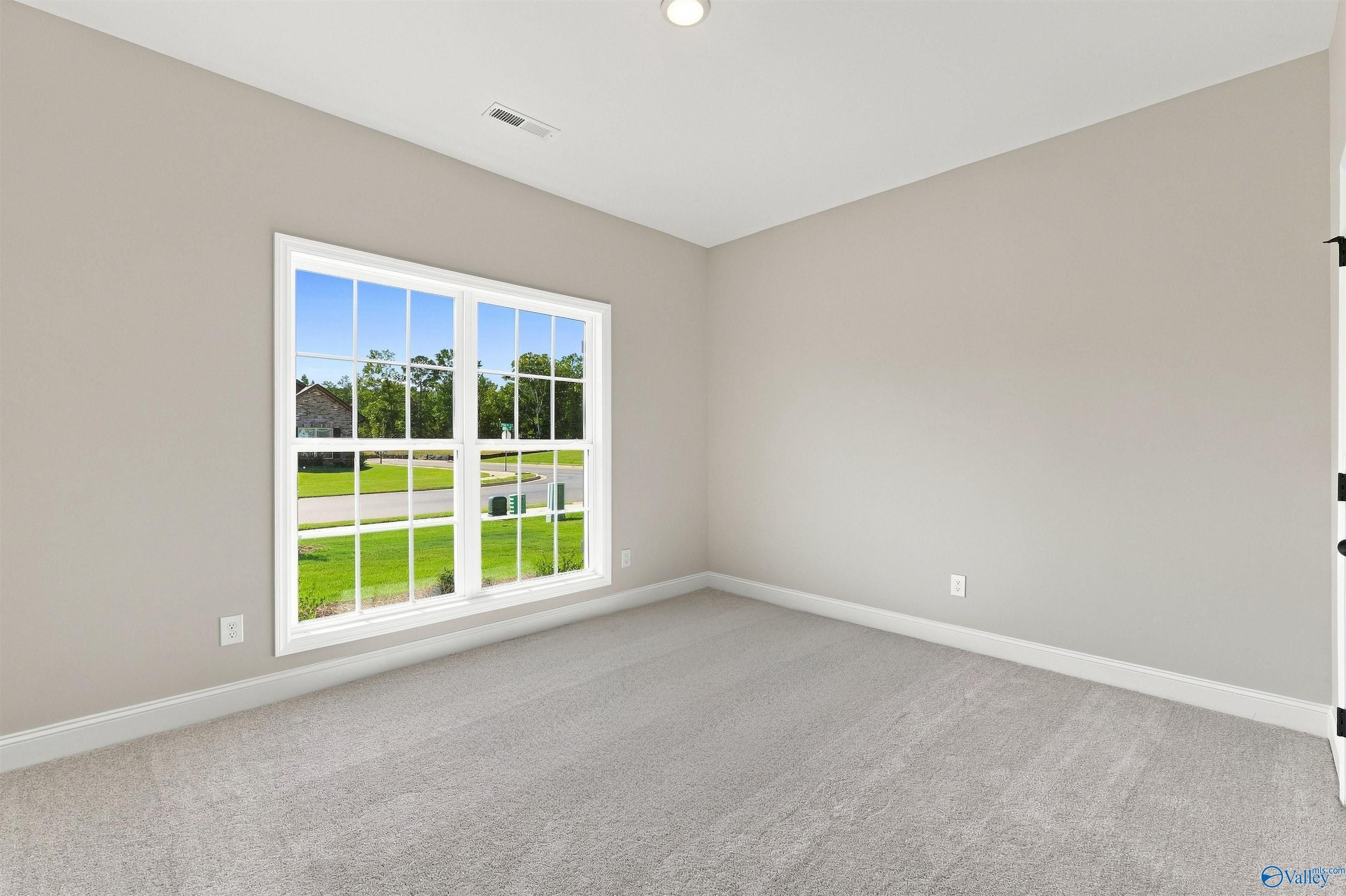Bright, carpeted bedroom with neutral walls and large windows in The Daphne floor plan at Spragins Cove, Huntsville.