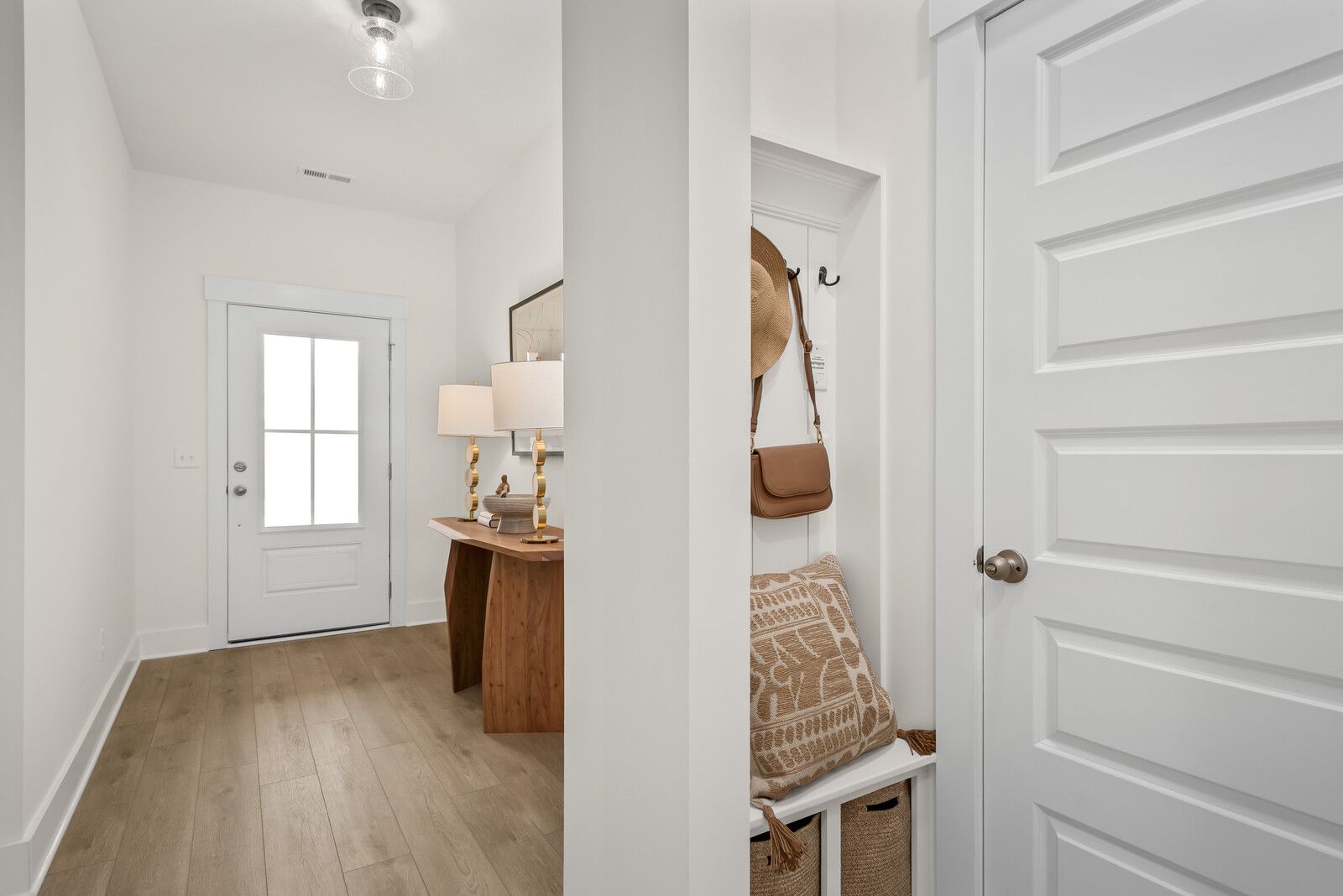 Bright Ridgeport E entryway with wooden console, lamps, bench, hat hooks, and storage baskets