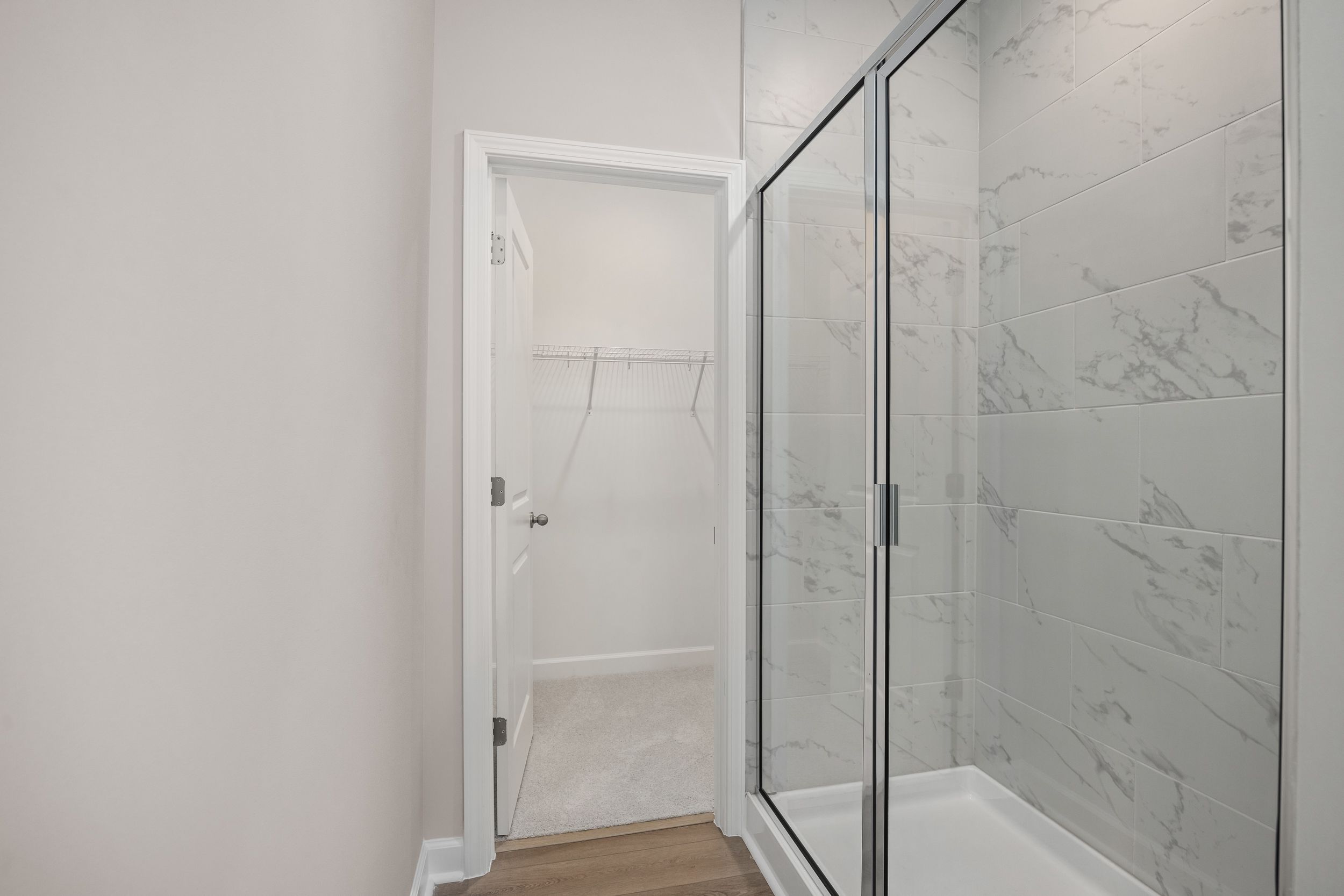 Spacious master bathroom in The Aspen C with glass-enclosed walk-in shower, white subway tiles, and open walk-in closet