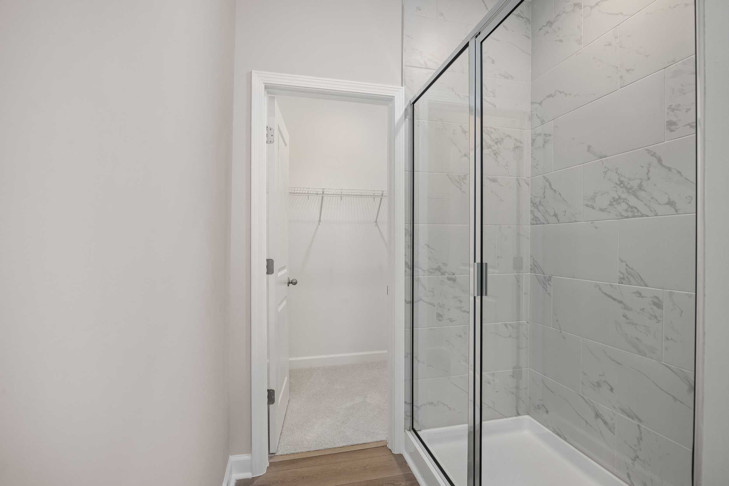 Spacious master bathroom in The Aspen C with glass-enclosed walk-in shower, white subway tiles, and open walk-in closet