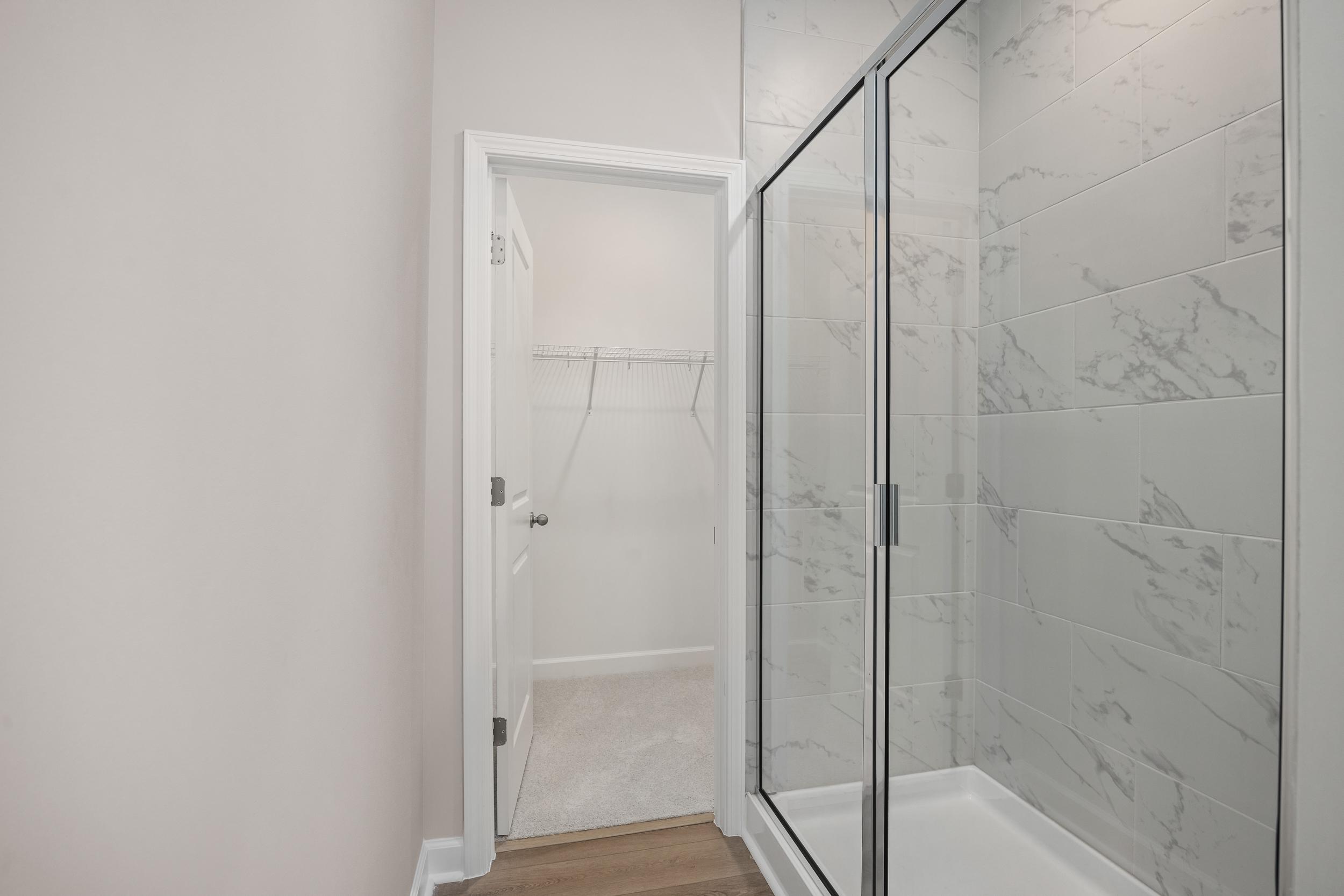 Spacious master bathroom in The Aspen C with glass-enclosed walk-in shower, white subway tiles, and open walk-in closet