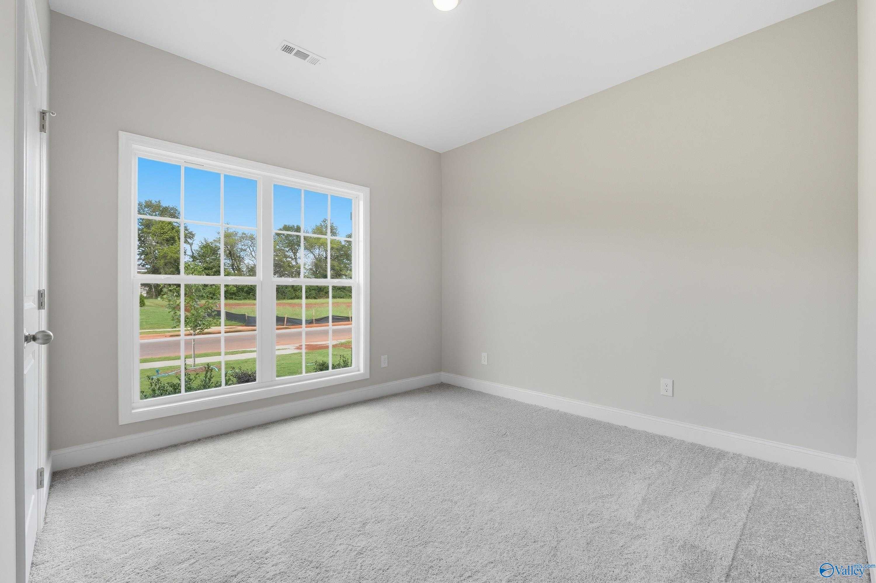 Bright secondary bedroom with large window view of lush greenery in Davidson Homes The Franklin, Meridianville, Alabama