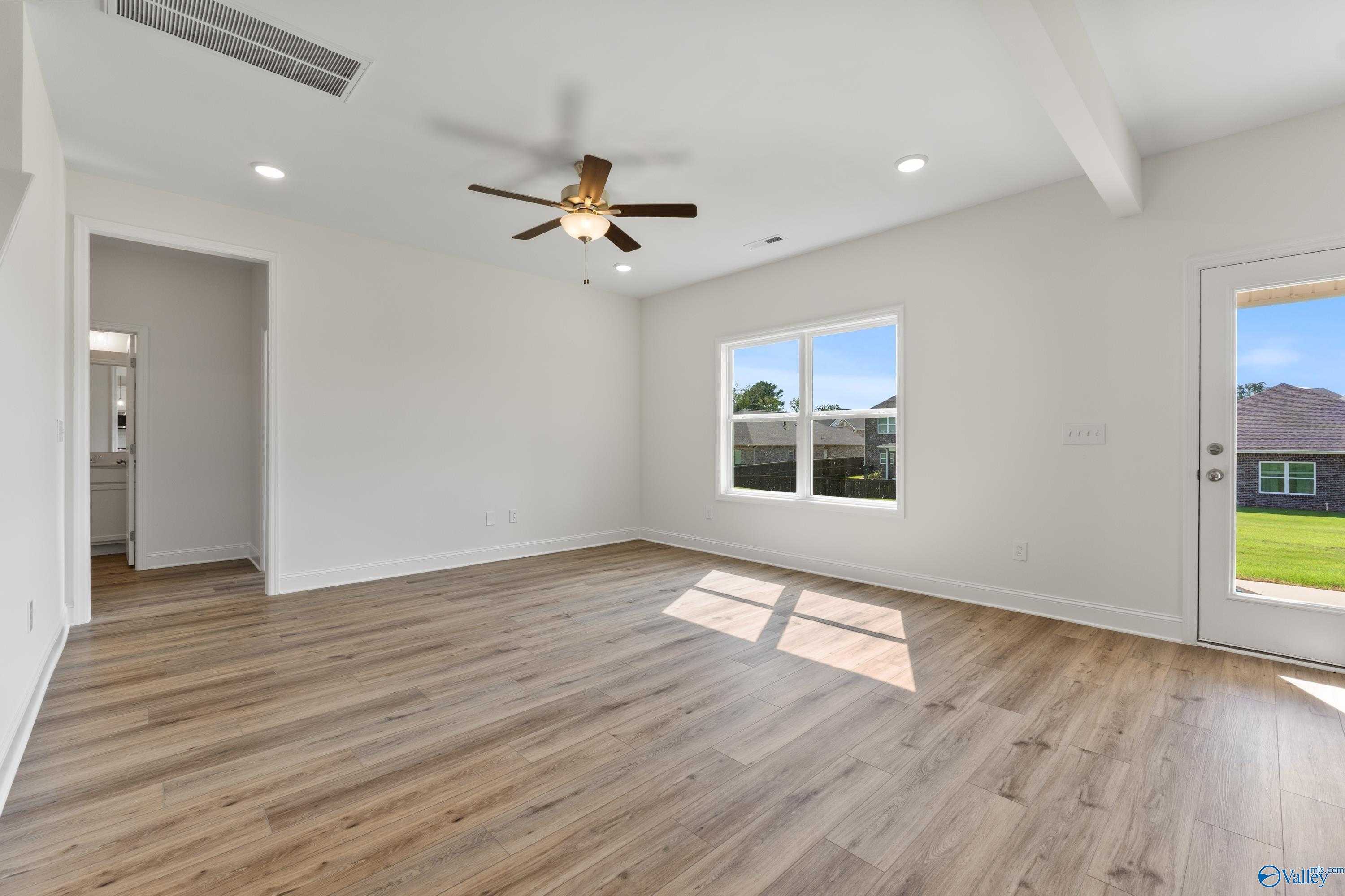 Bright family room with hardwood floors, ceiling fan, large windows, and sliding doors to lush backyard in Davidson Homes The Shelby A, New Market, Alabama