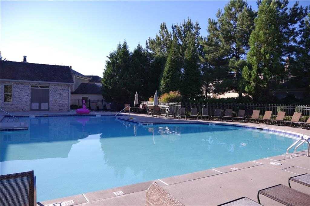 Inviting turquoise community pool with lounge chairs, umbrellas, and trees in The Village at Towne Lake, Woodstock, Georgia