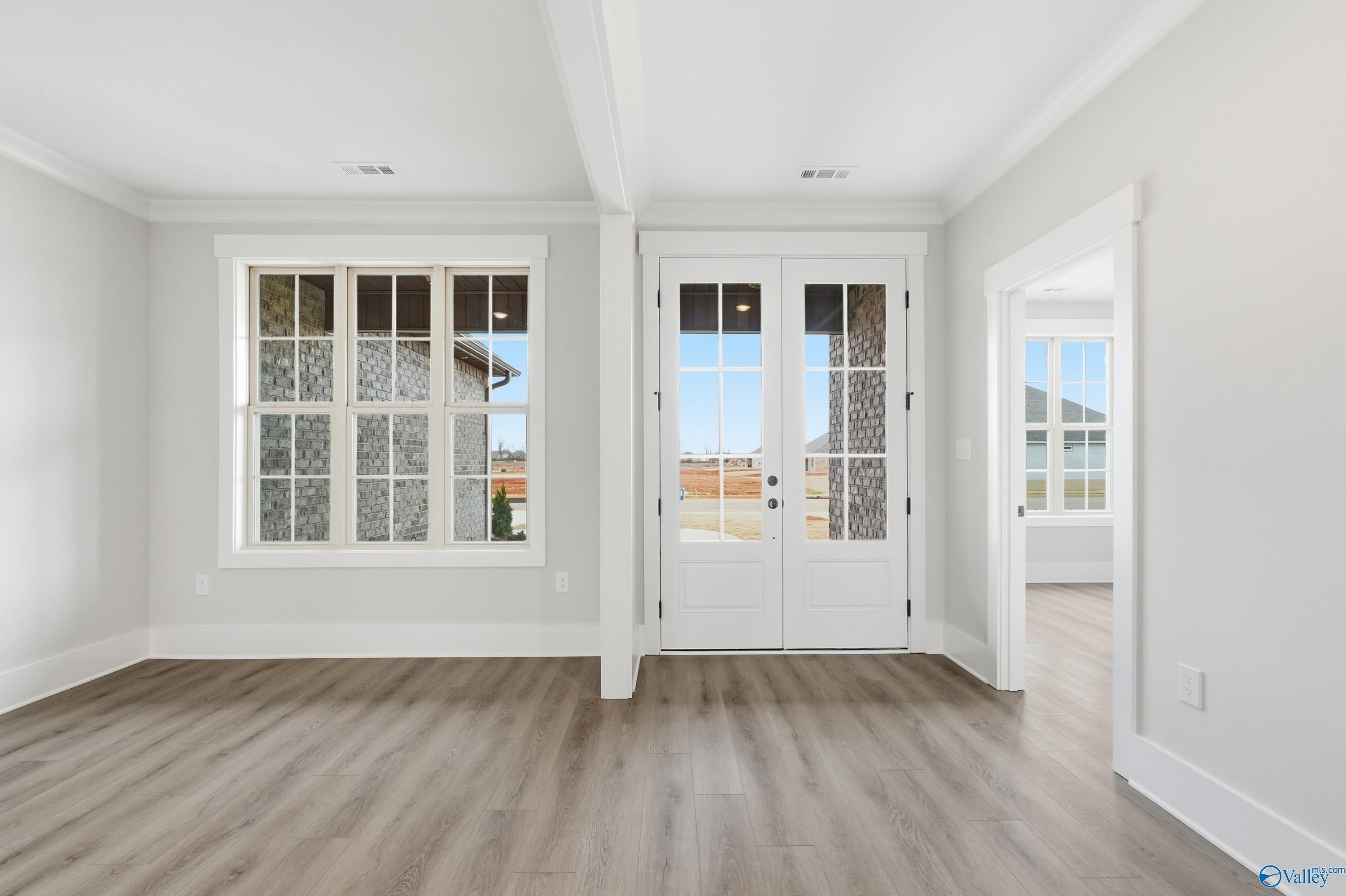 Bright living room with hardwood floors, large grid windows, and white French doors in Davidson Homes The Finleigh, Meridianville, AL