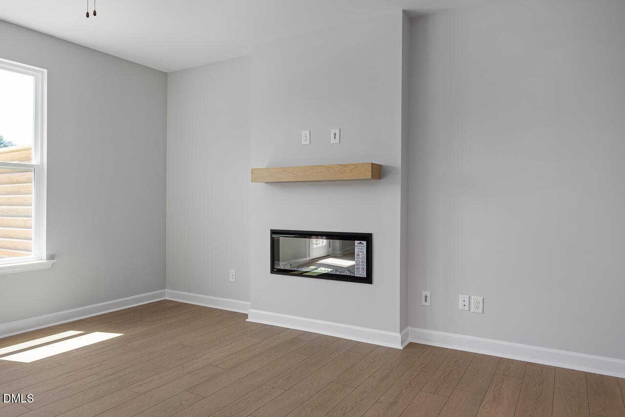Modern living room with fireplace and wood mantel in The Mitchell floor plan at Camden Park, Knightdale, North Carolina.