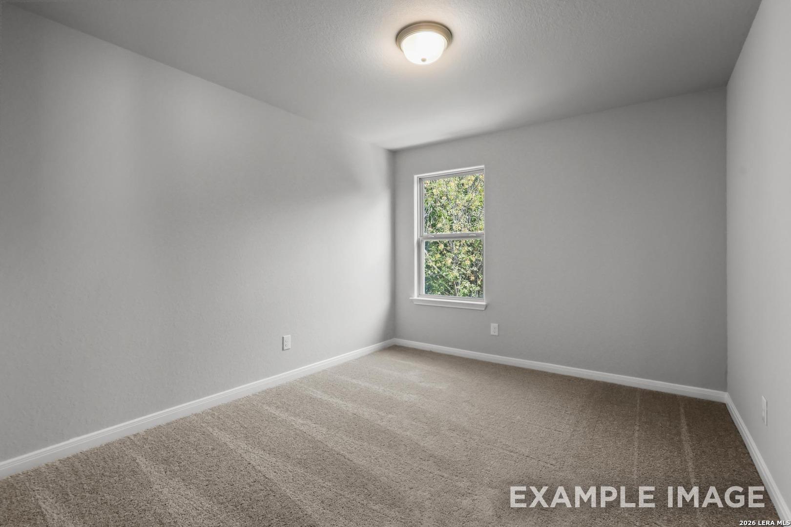 Bright, carpeted bedroom with neutral walls and a window in The Gillian A floor plan at Cedar Heights, San Antonio.