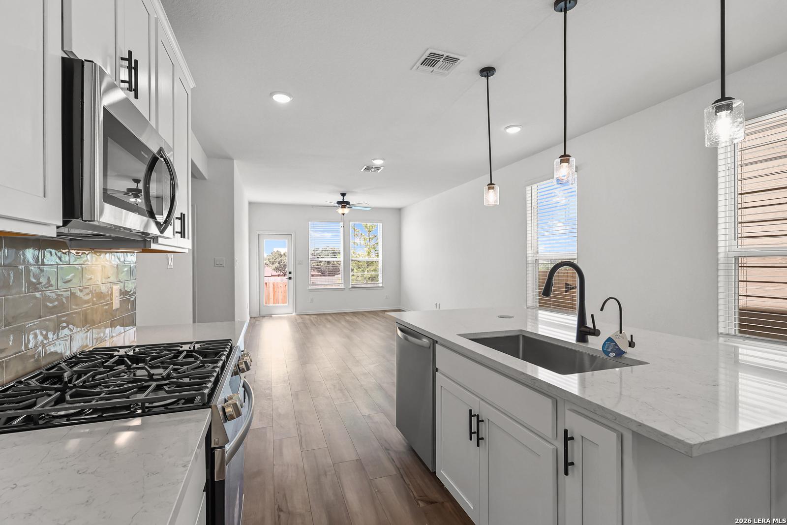 Modern kitchen with white cabinets and island in The Gillian C floor plan at Meadows at Oak Creek, San Antonio, Texas.