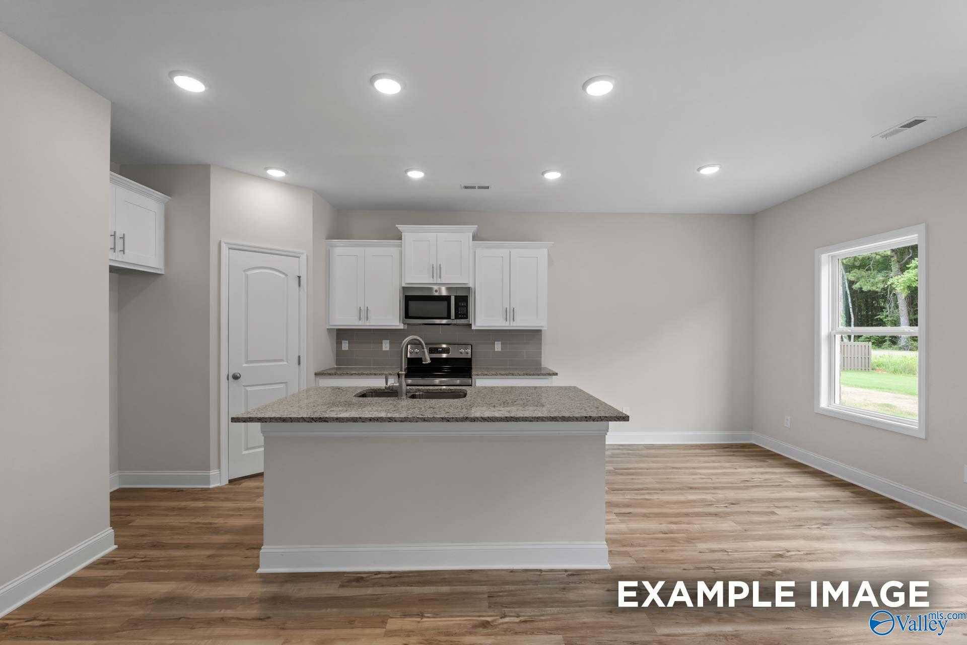 Modern kitchen featuring white shaker cabinets, granite island sink, stainless appliances in Davidson Homes The Butler, Toney, AL