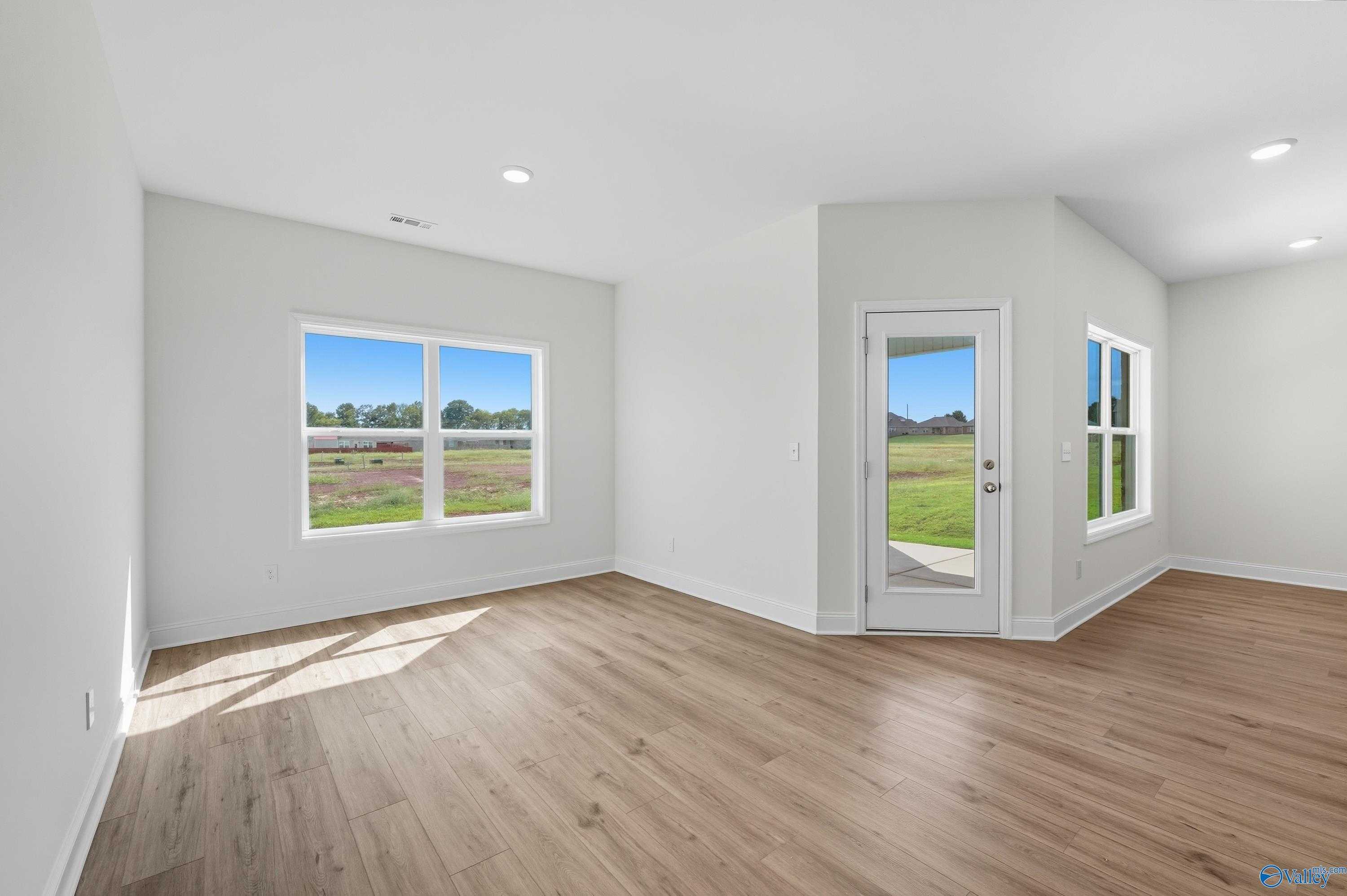 Bright family room with large windows and sliding glass door overlooking green yard in Davidson Homes The Everett, Meridianville, Alabama