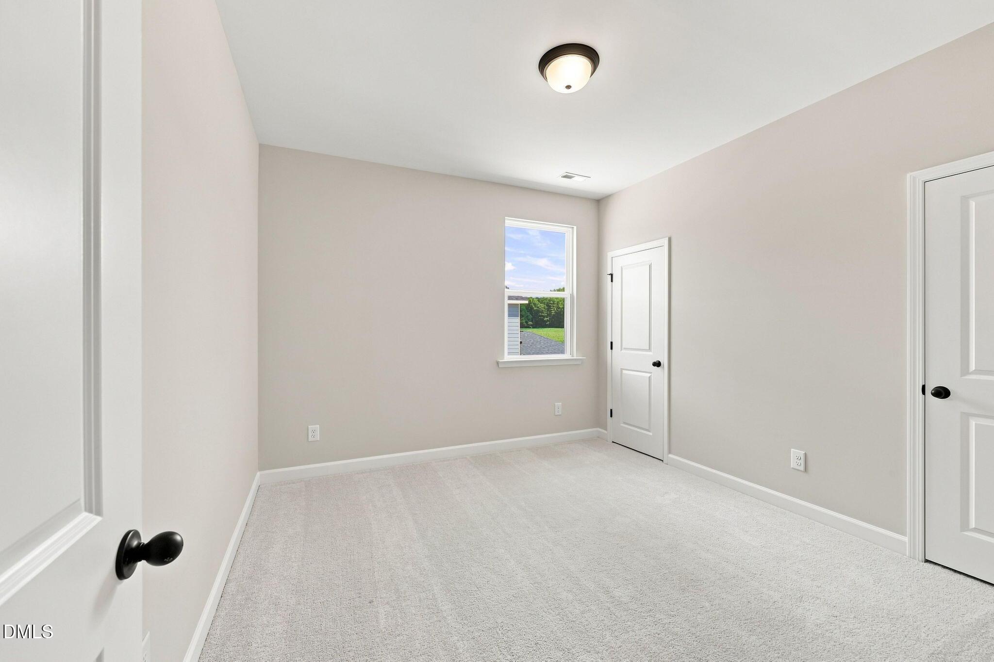 Spacious carpeted bedroom with neutral paint in The Harris C floor plan at Forestville Yard, Knightdale, North Carolina.