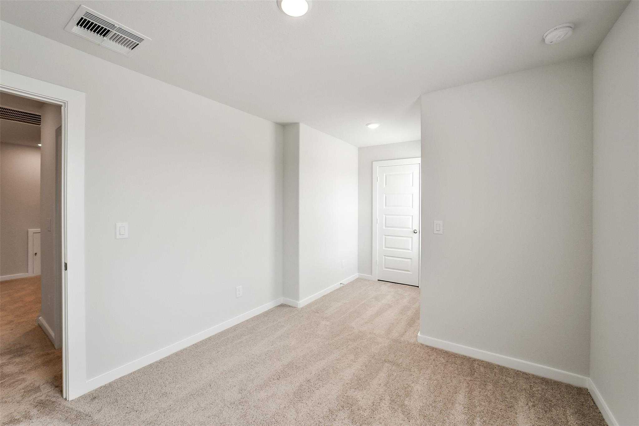 Spacious carpeted upstairs hallway with white doors and neutral walls in 4-bedroom Davidson Homes The Blanco E, Magnolia, Texas