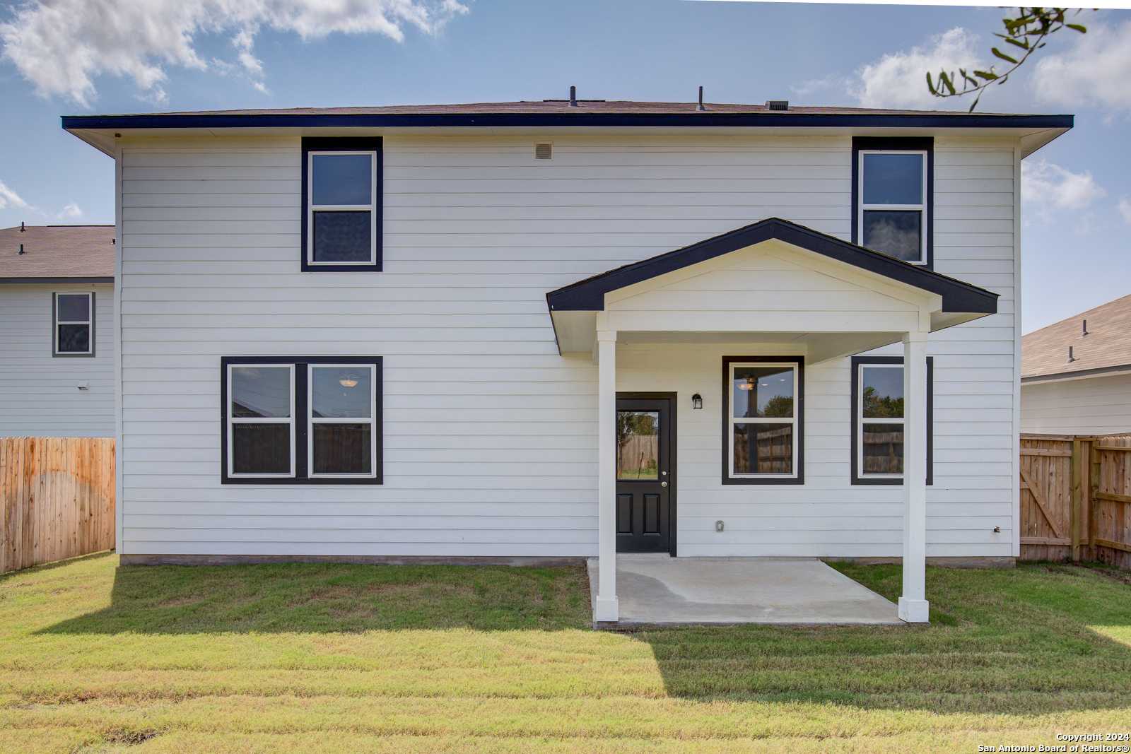Back exterior of two-story Douglas D home with covered porch, black-trimmed windows, and fenced grassy yard in Hannah Heights, Seguin, Texas