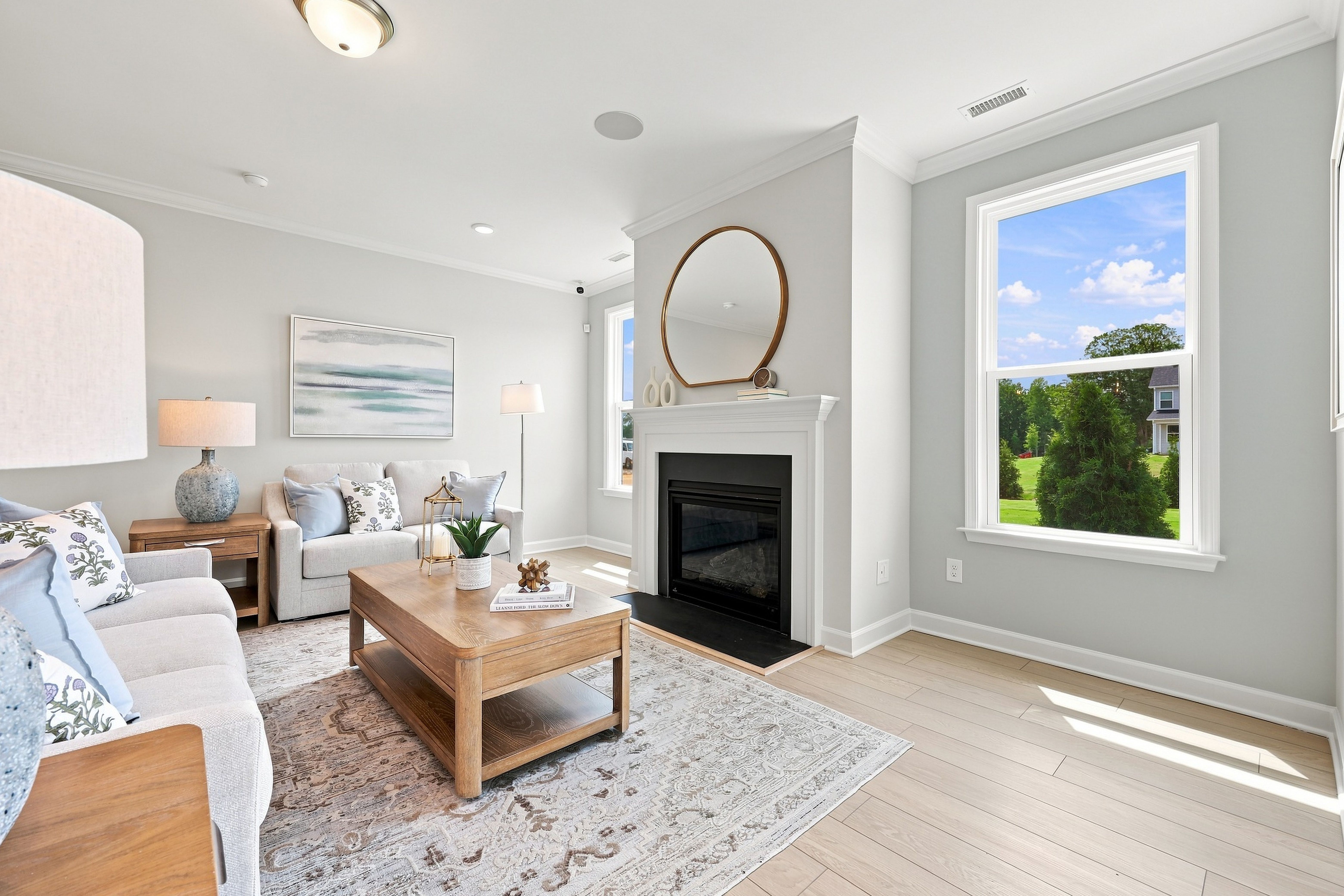 Bright living room in The Daphne D featuring a cozy fireplace, light wood flooring, and stylish open-concept decor.