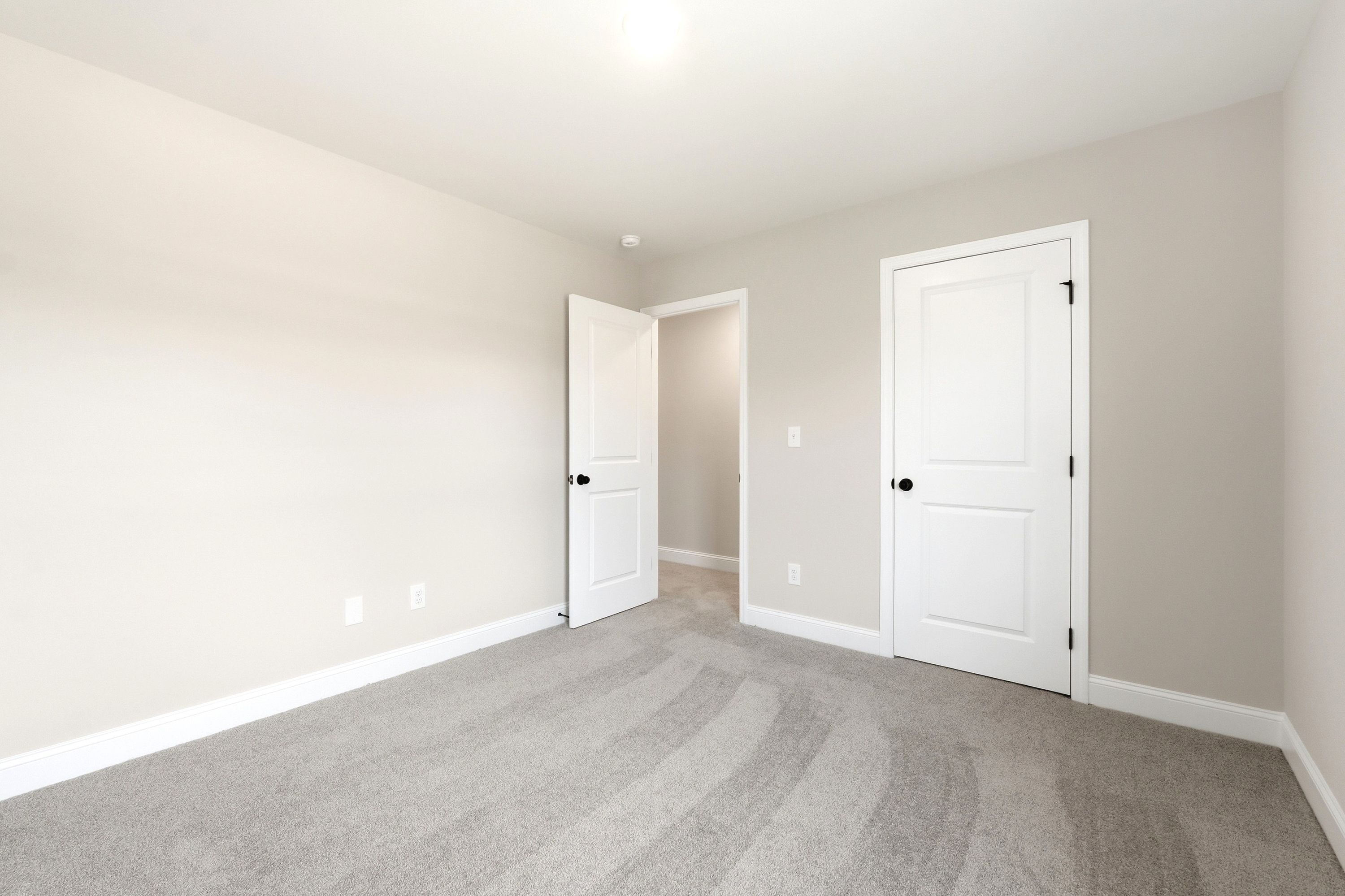 Spacious secondary bedroom in The Russell A featuring neutral paint, plush carpeting, and a walk-in closet.
