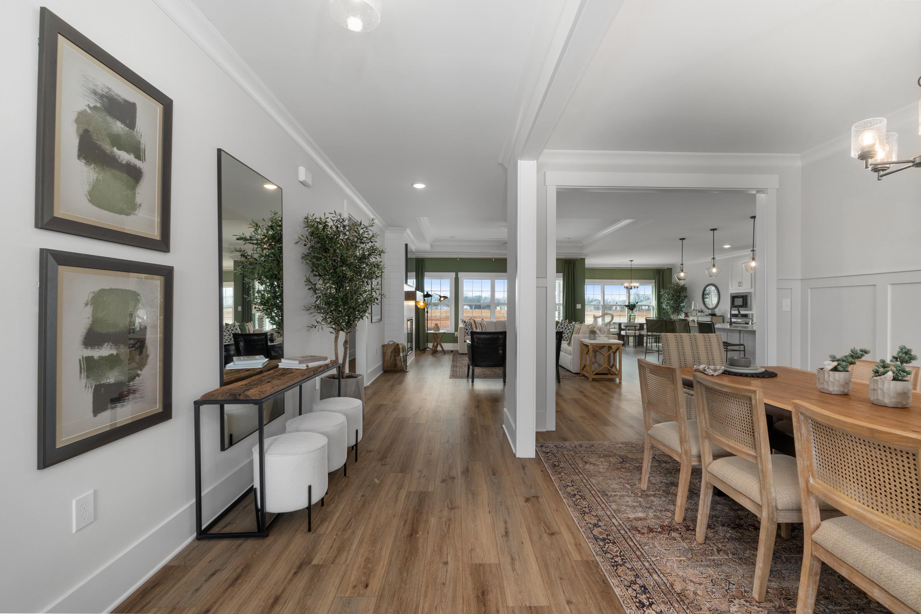 Spacious hallway and dining area at Briercreek in Meridianville, Alabama with hardwood floors, modern artwork, and rattan chairs