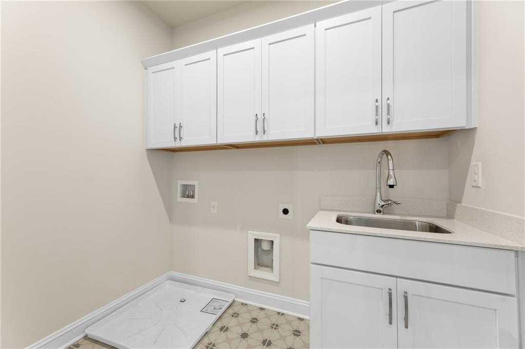 Modern laundry room with white shaker cabinets, utility sink, and washer/dryer space in Davidson Homes The Hampton C, Buford, GA