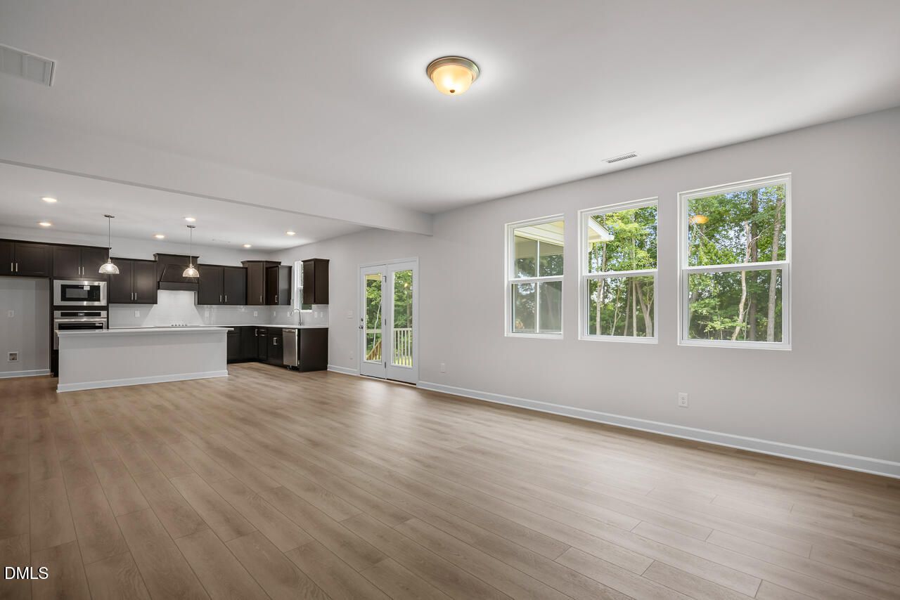 Open-concept living space with hardwood floors and modern kitchen in The Hickory II B home in Lillington, North Carolina.