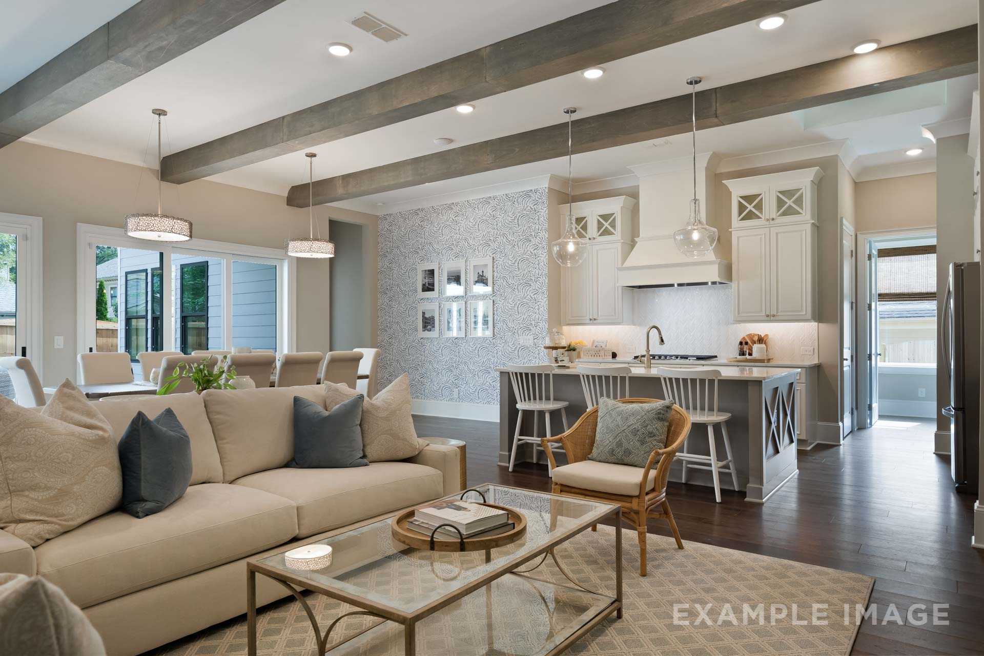 Spacious open-concept living room and kitchen in The Seaside by Davidson Homes featuring beige sofa, white island, beamed ceiling