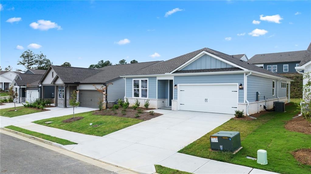 Modern light blue single-story home with 2-car garage, shake shingle roof, and landscaped driveway in Kelly Preserve, Loganville, Georgia
