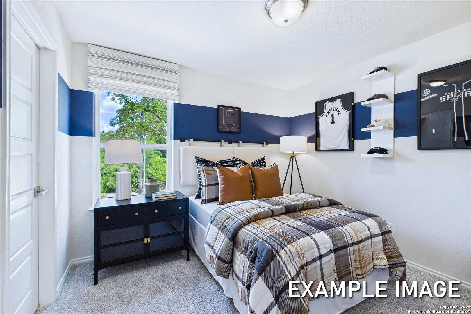 Cozy youth bedroom with navy blue accent wall, sports jersey decor, plush plaid bed in Davidson Homes The Gillian C, San Antonio, Texas