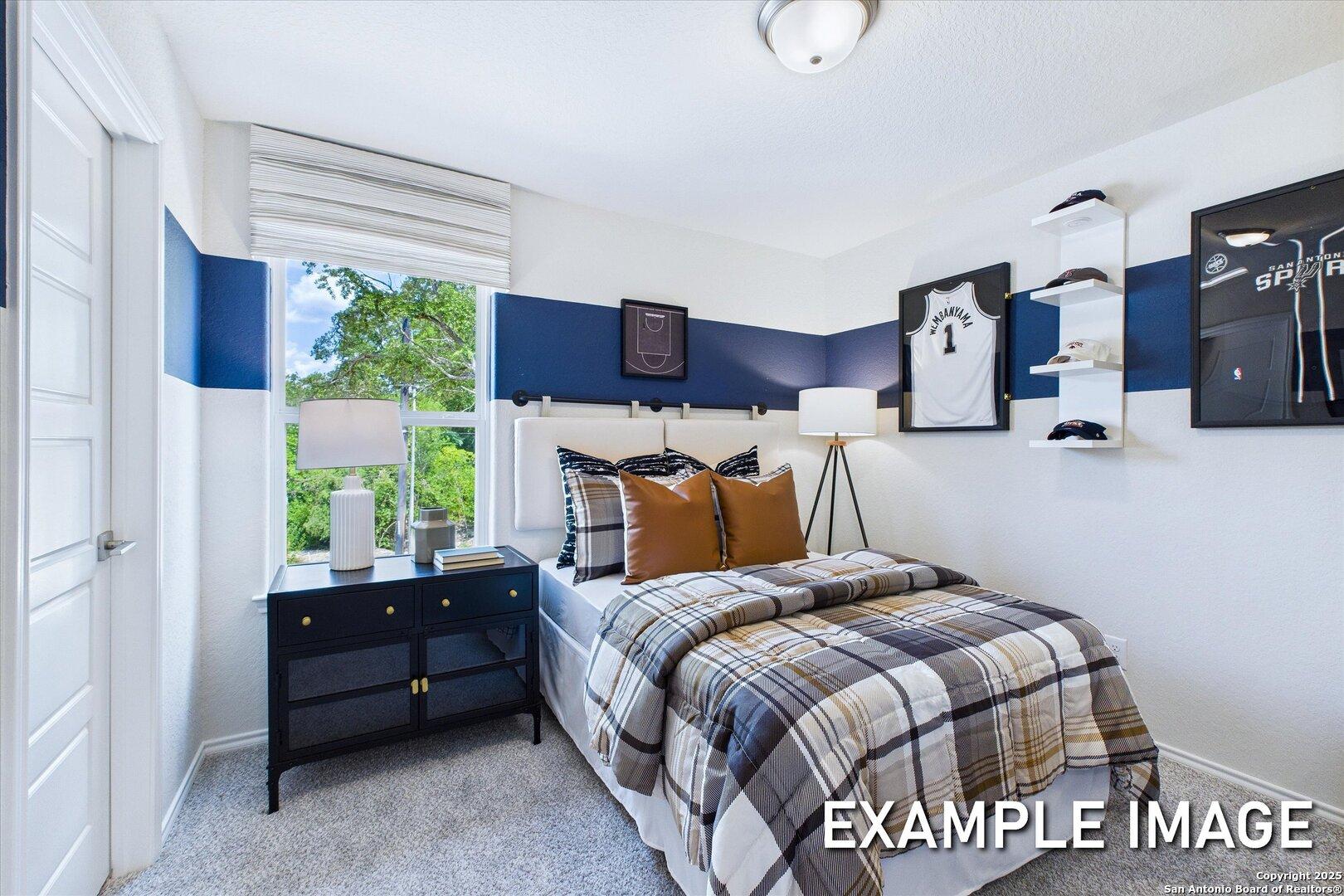 Cozy boy's bedroom with blue accent wall, sports jersey and hat decor, plaid bed in Davidson Homes The Gillian C, San Antonio