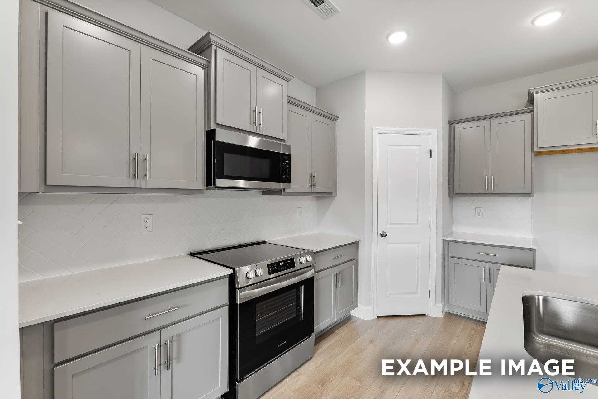 Modern kitchen featuring gray shaker cabinets, stainless steel oven and microwave, white quartz counters in Davidson Homes The Franklin C, Toney, AL
