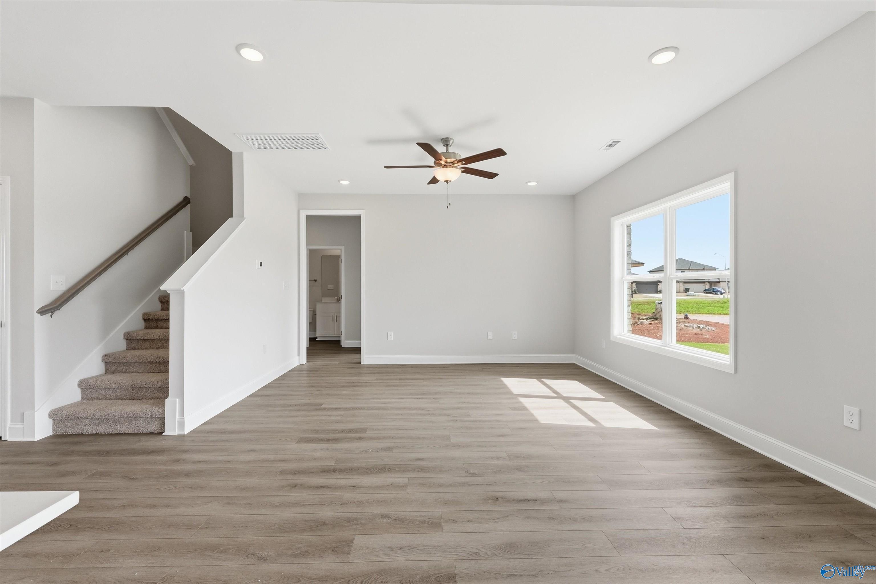 Bright, open-concept living area with wood-style flooring in The Shelby D plan at Evergreen Mill, Madison, Alabama.