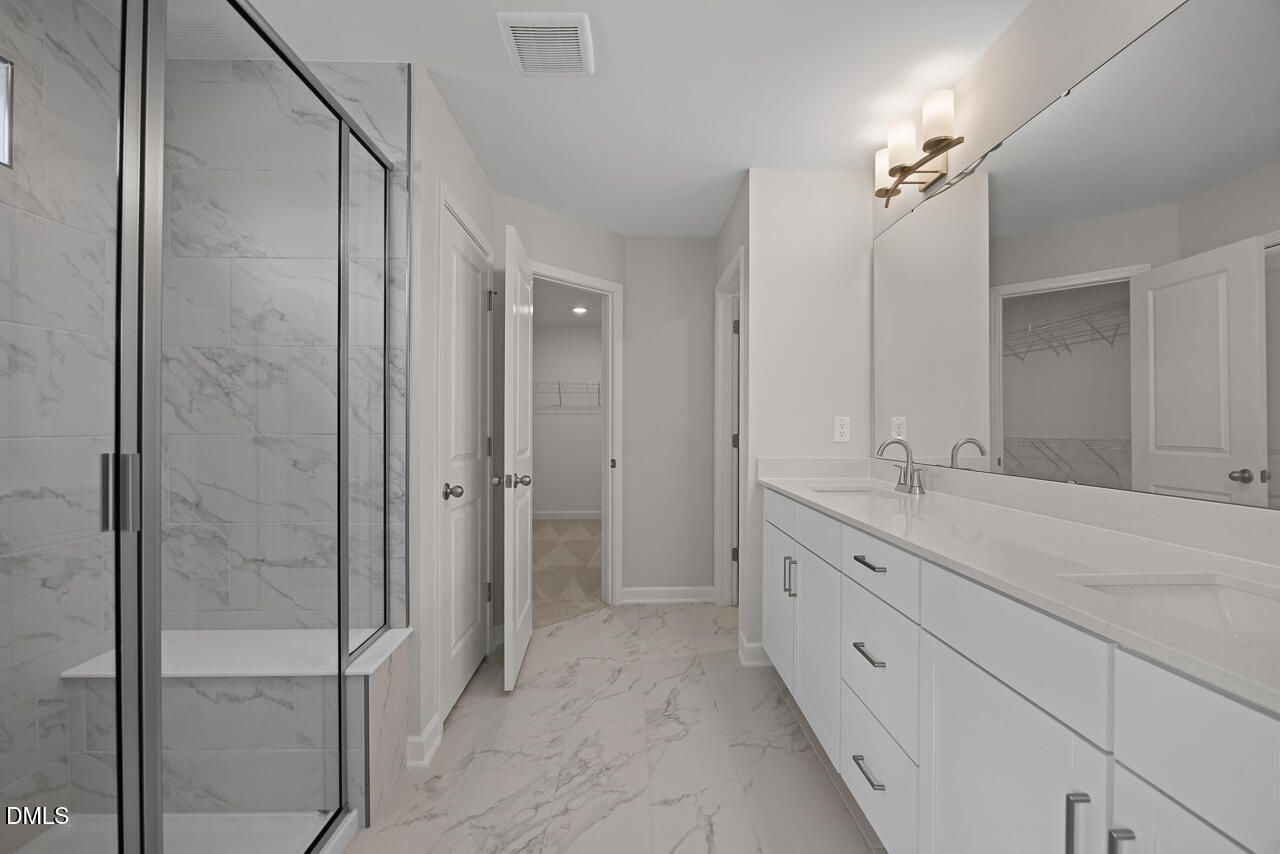Modern primary bathroom with marble-style tile, dual vanity, and walk-in shower in The Chestnut plan at Wendell Ridge.