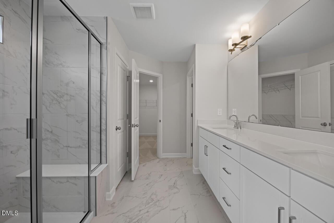 Modern primary bathroom with marble-style tile, dual vanity, and walk-in shower in The Chestnut plan at Wendell Ridge.