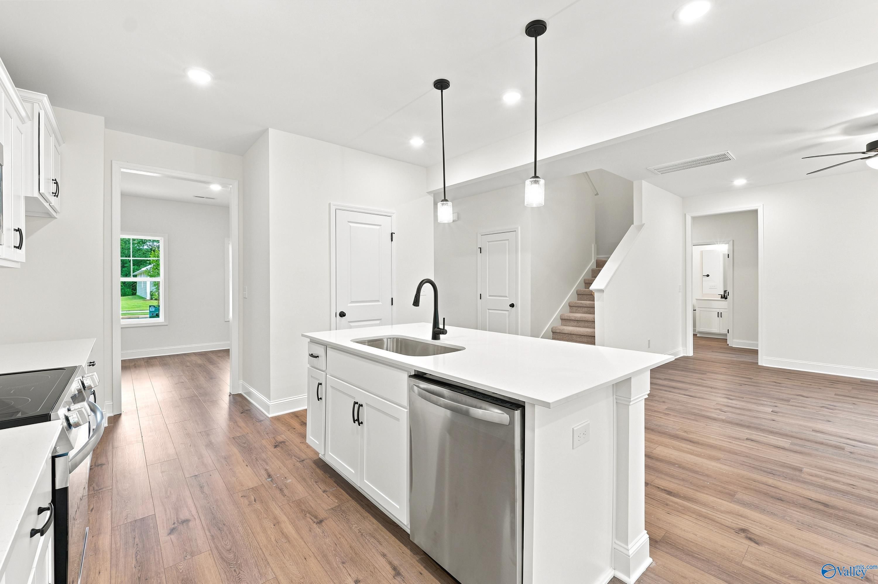 Modern kitchen island with quartz countertops and stainless steel appliances in The Shelby D home, Noble Ridge, Cullman, AL.