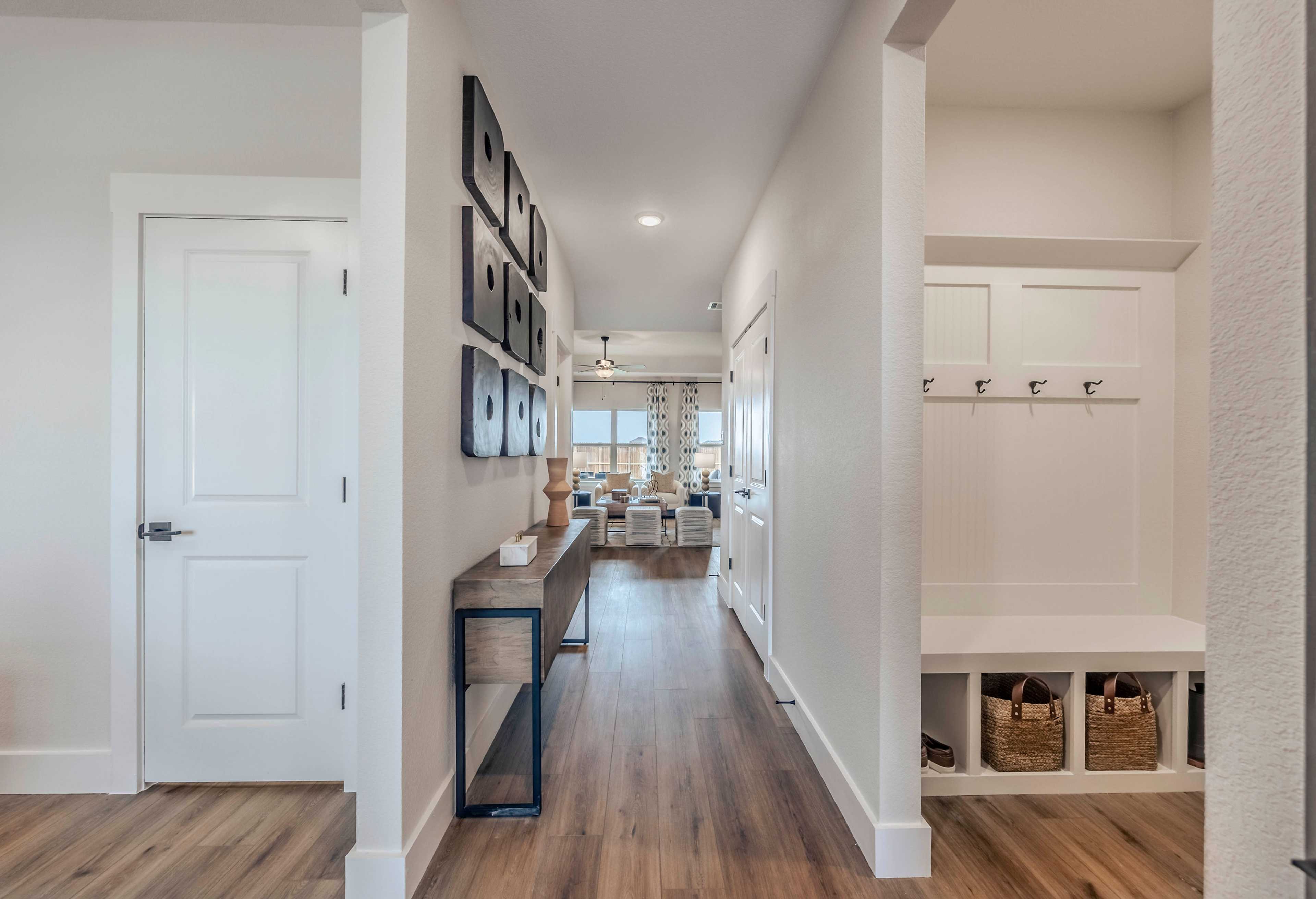 Spacious foyer in The Rockford by Davidson Homes with white walls, hardwood floors, framed art, console table, and open living room view