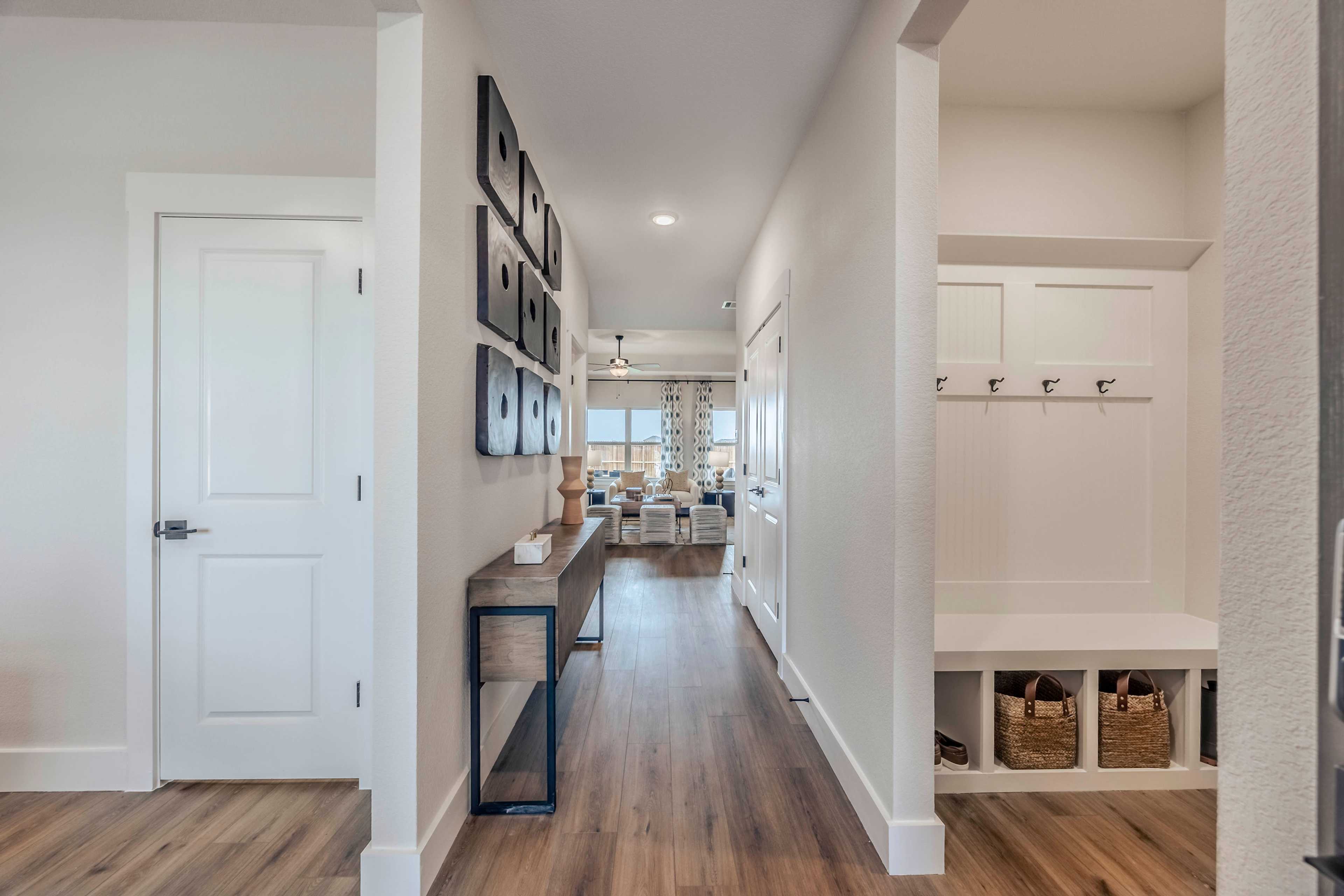 Spacious entryway in The Rockford home with white walls, hardwood floors, console table, framed art, and built-in mudroom bench