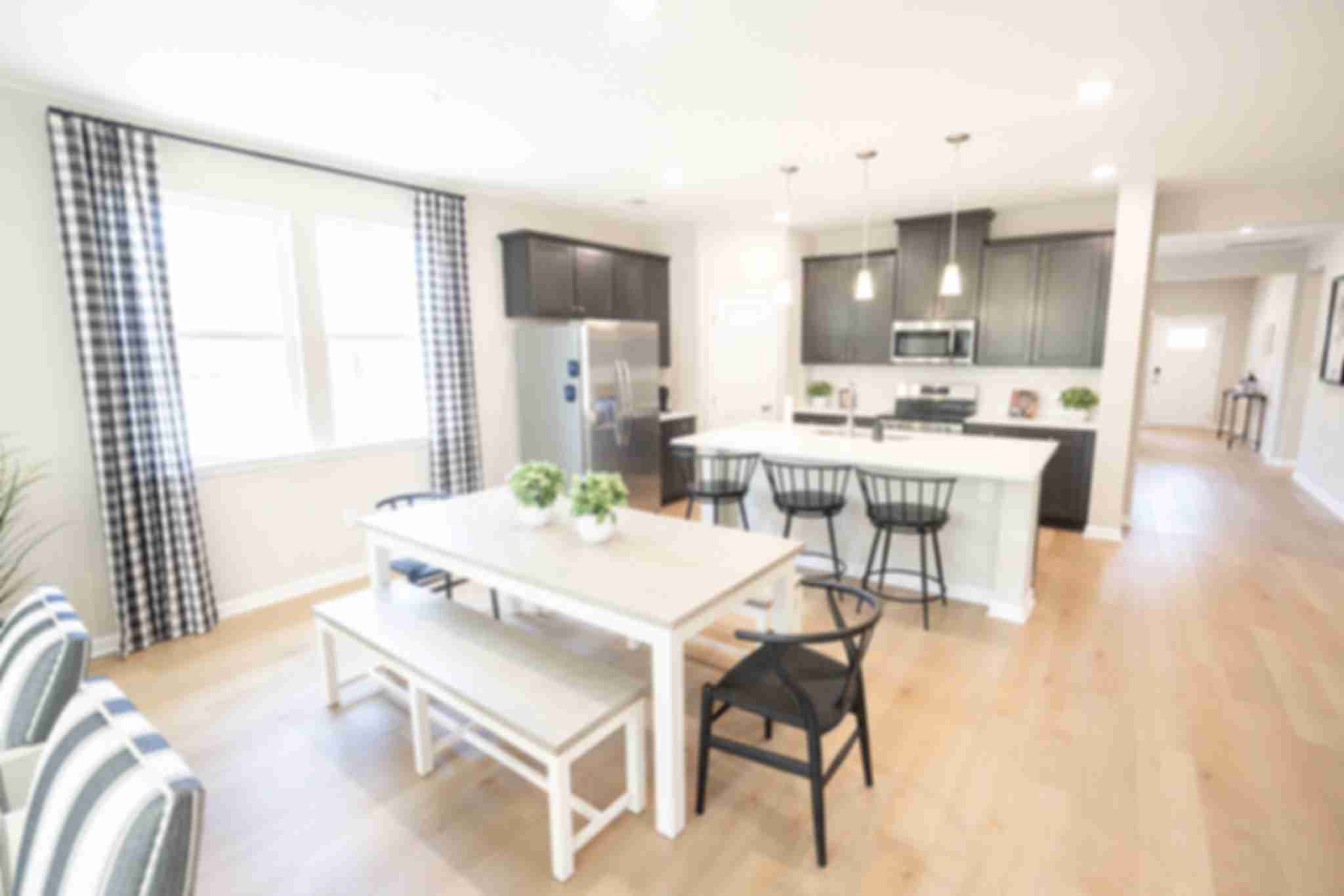 Spacious open-concept kitchen at Silver Oak in Cusseta Alabama with dark cabinets white island farmhouse table and hardwood floors