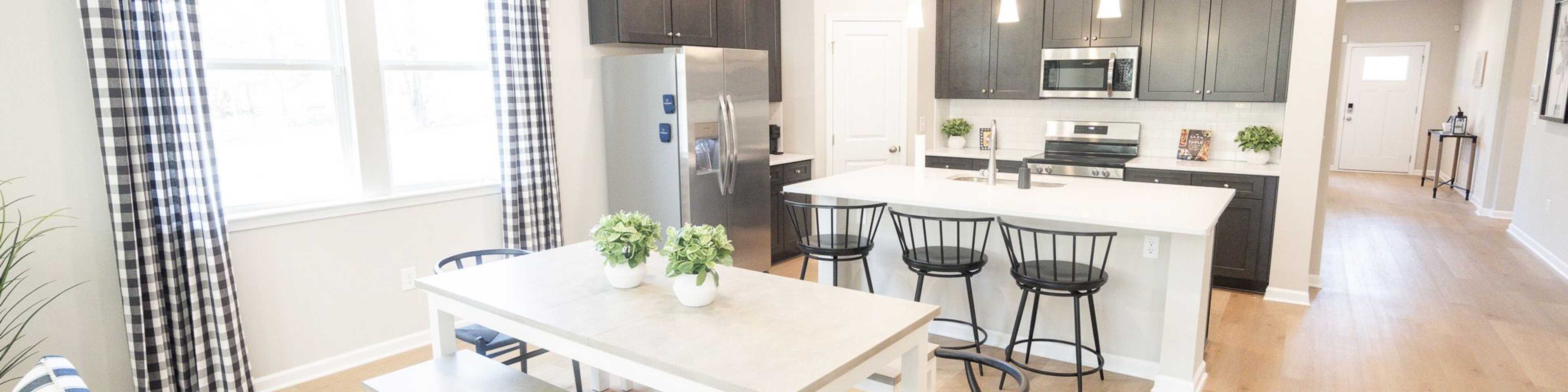 Spacious open-concept kitchen at Silver Oak in Cusseta Alabama with dark cabinets white island farmhouse table and hardwood floors