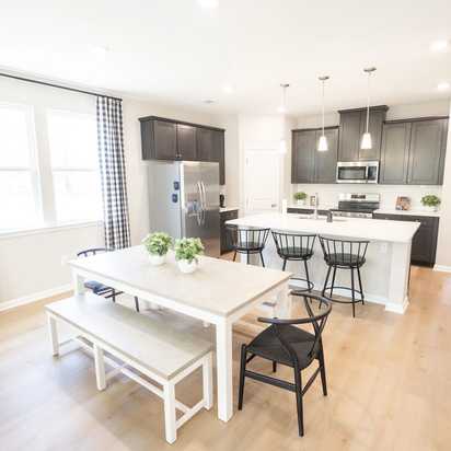 Spacious open-concept kitchen at Silver Oak in Cusseta Alabama with dark cabinets white island farmhouse table and hardwood floors