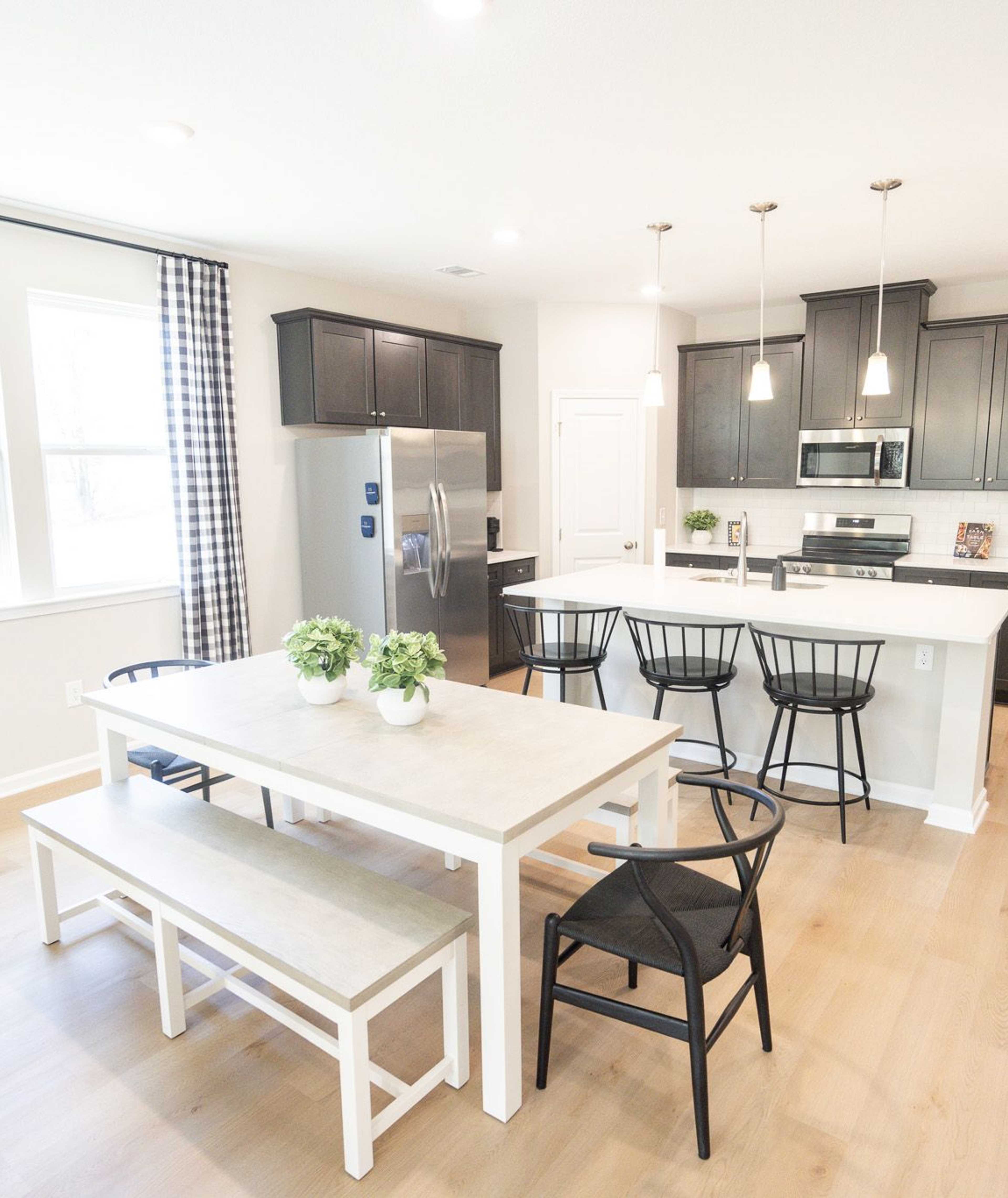 Spacious open-concept kitchen at Silver Oak in Cusseta Alabama with dark cabinets white island farmhouse table and hardwood floors