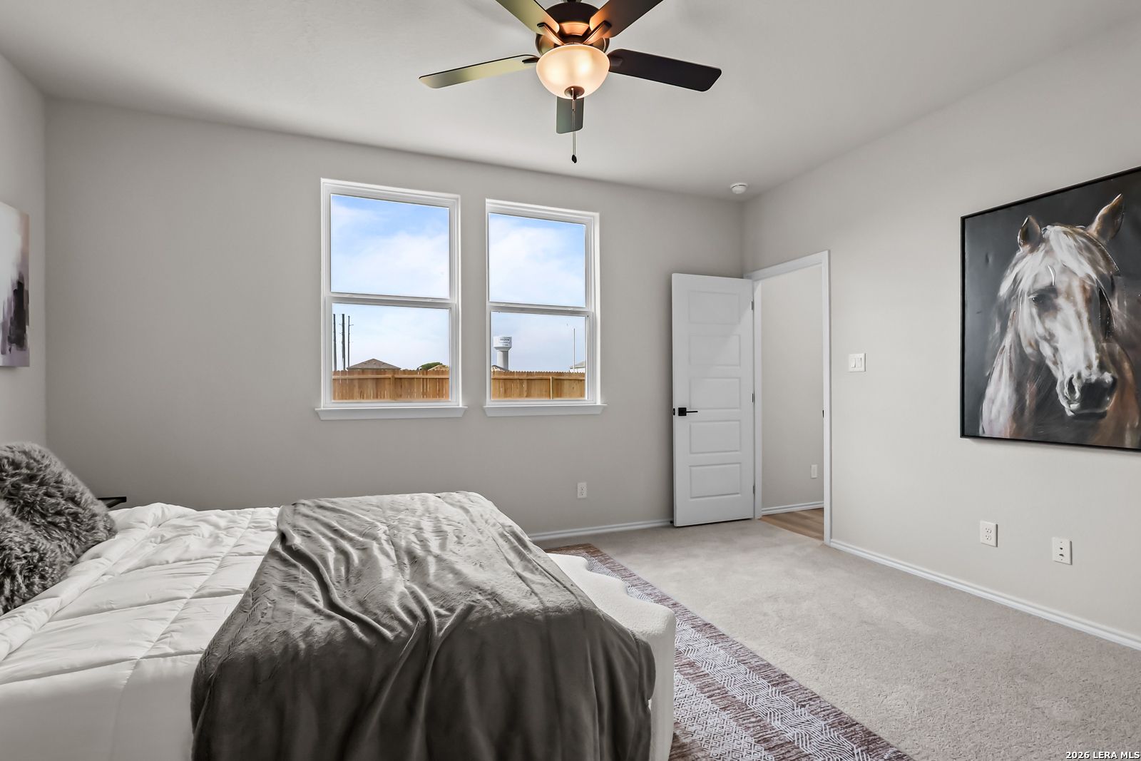 Spacious bedroom with neutral decor, ceiling fan, and large windows in The Douglas C floor plan at Hannah Heights, Seguin.