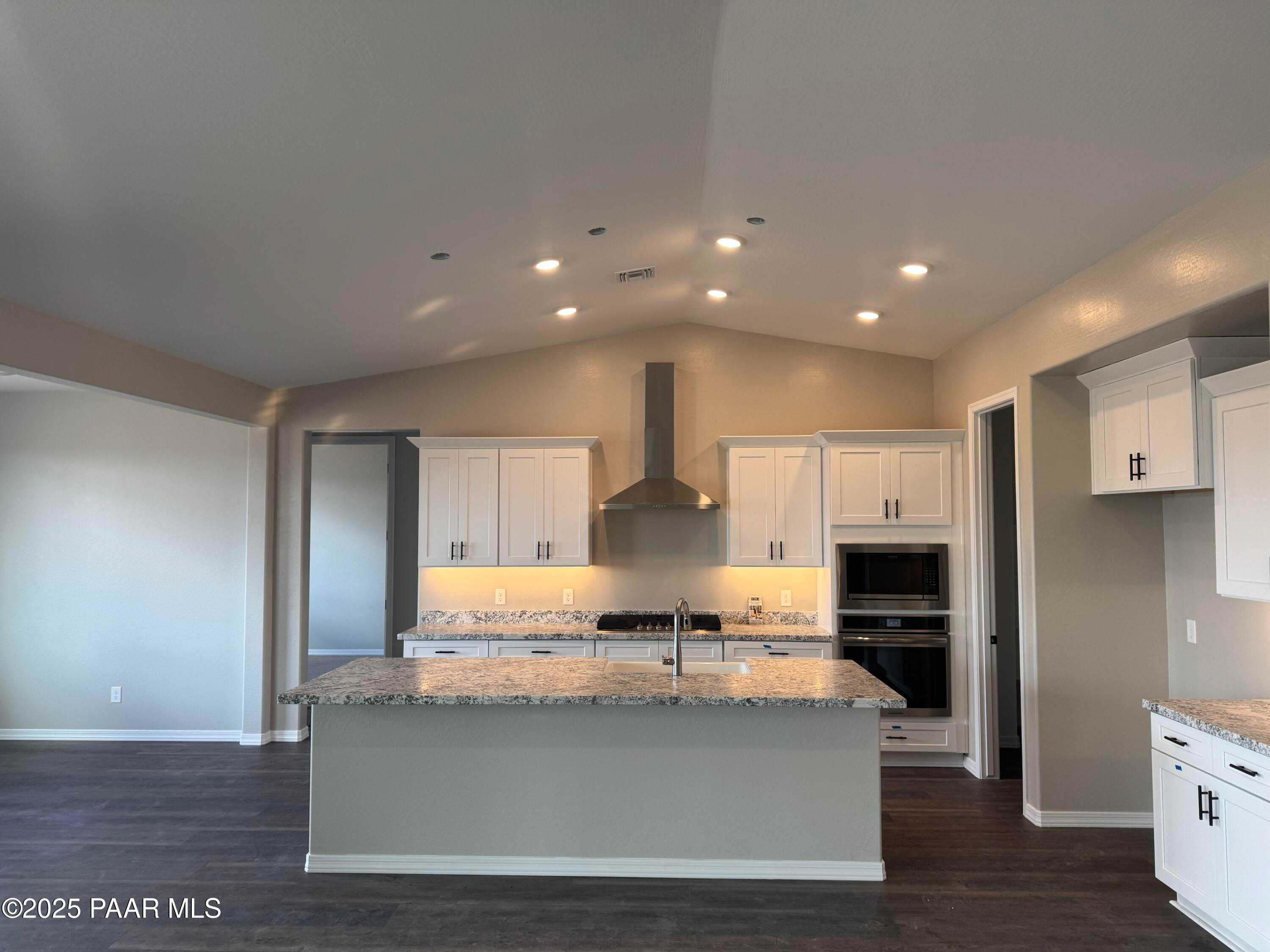 Modern white kitchen with granite island, stainless steel appliances, and range hood in Davidson Homes The Monarch E, Prescott AZ
