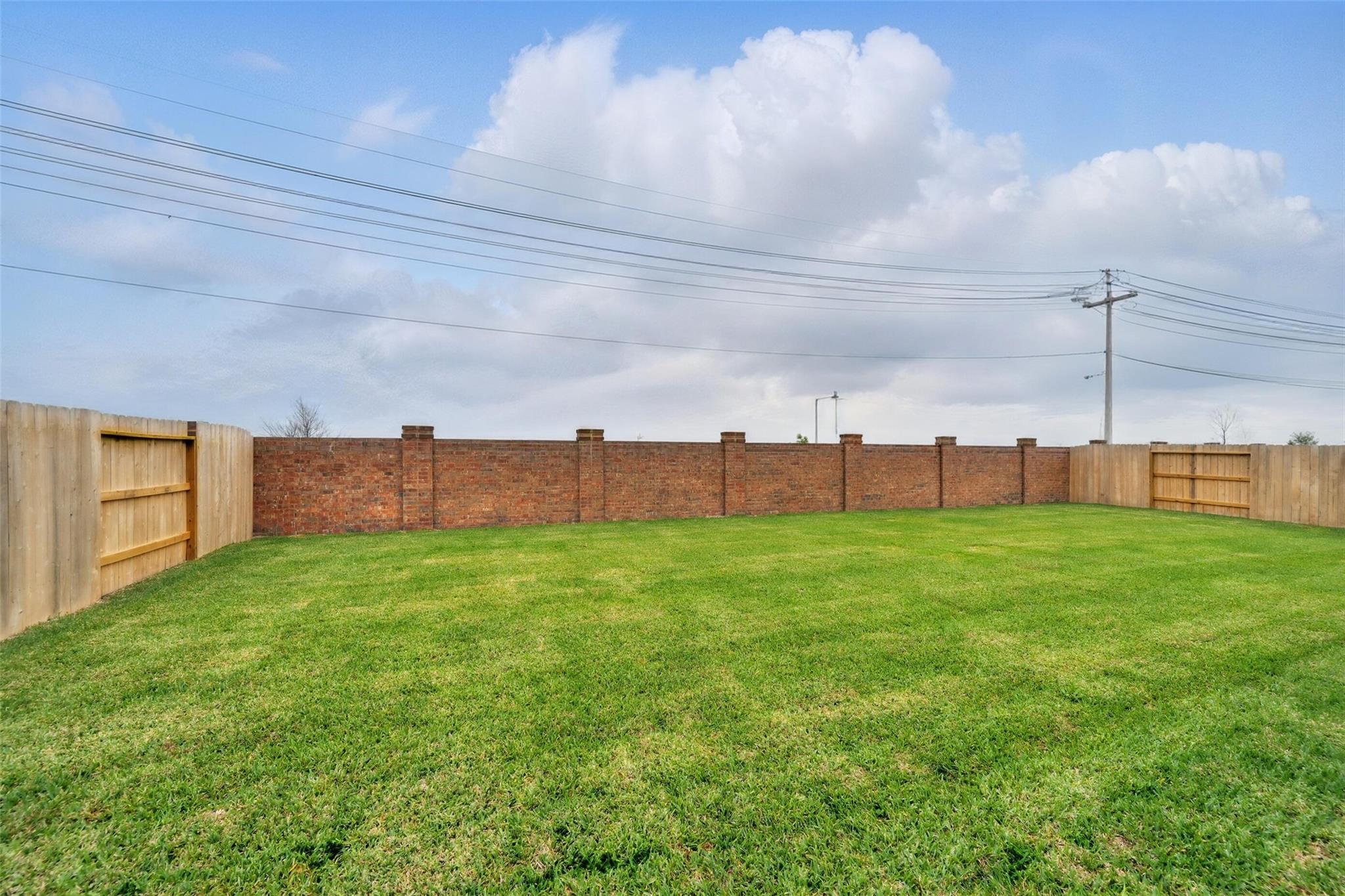 Expansive grassy backyard with wooden and brick fences in Davidson Homes The Philip A, Lago Mar, Texas City, Texas