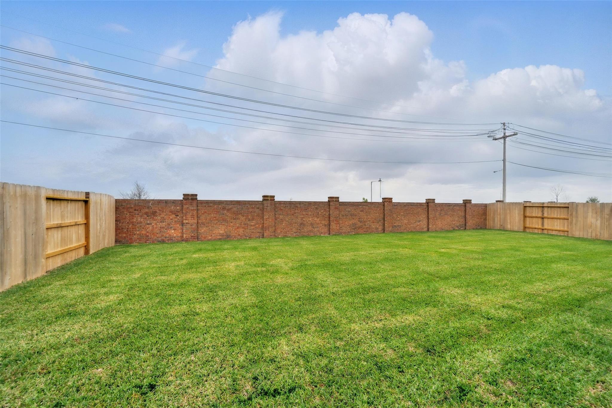 Expansive grassy backyard with wooden and brick fences in Davidson Homes The Philip A, Lago Mar, Texas City, Texas