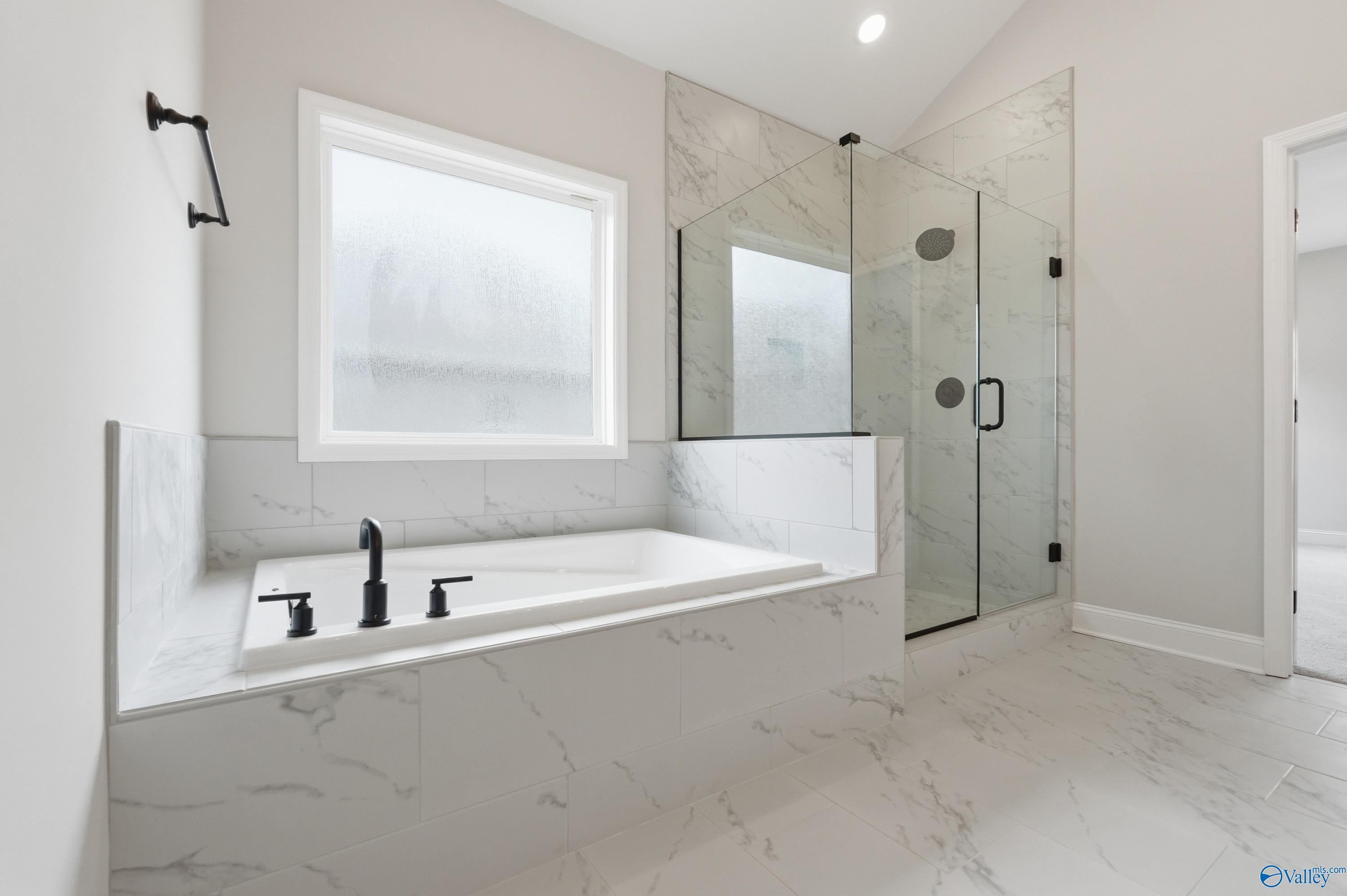 Modern master bathroom with freestanding tub, glass shower, white marble tiles in Davidson Homes The Finleigh, Meridianville, Alabama