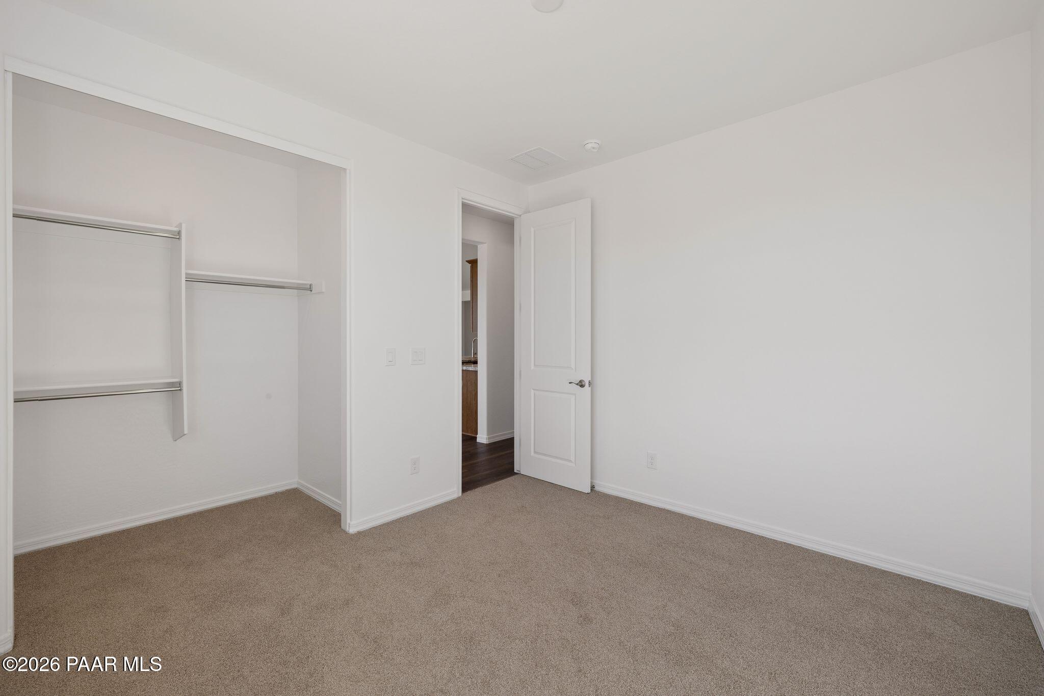 Spacious secondary bedroom with built-in closet, beige carpet, and en-suite bath access in Davidson Homes The Monarch A, Prescott, AZ