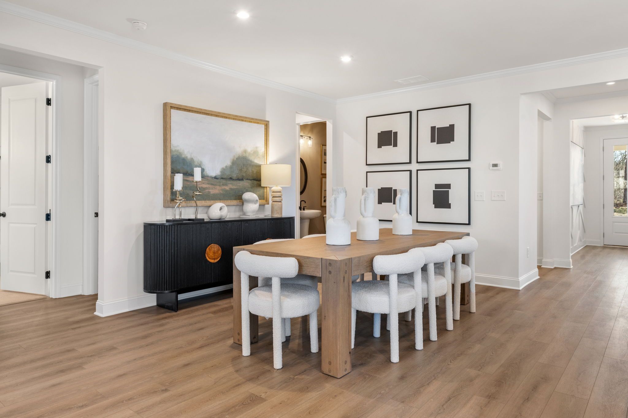Modern dining room in Fern Hollow Buford GA with oak table, white chairs, black credenza and abstract wall art