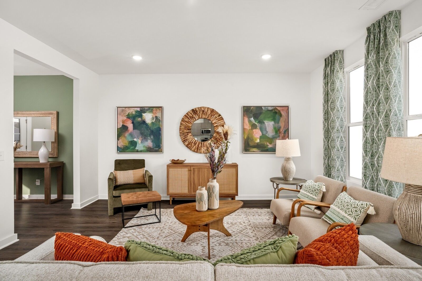 Stylish living room with abstract art, rattan mirror, mid-century coffee table, velvet chair, and plush sofa in Davidson Homes The Gordon C, White House TN