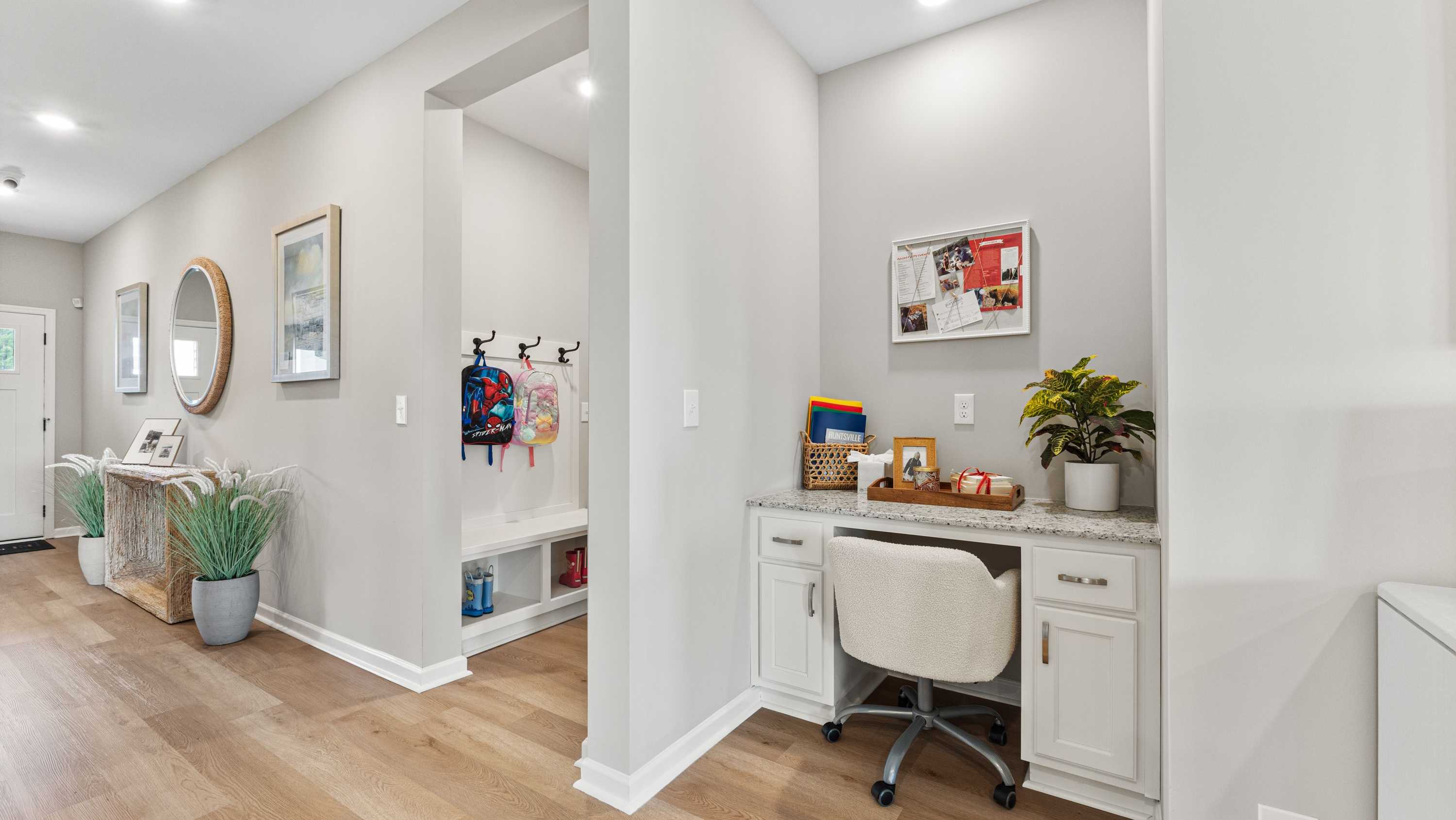 Built-in drop zone with backpack hooks and a small desk area for organizing school essentials in a modern home entryway.