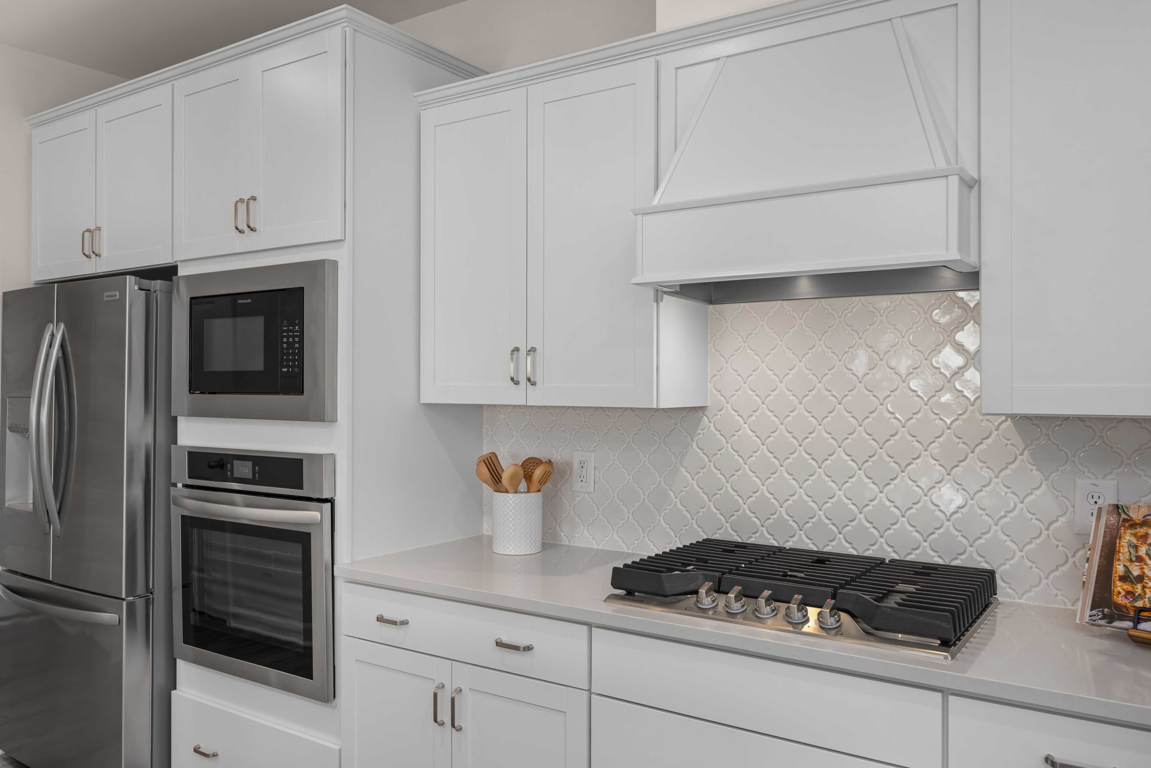 Spacious white shaker kitchen in Sage on North Main, Wake Forest NC with stainless steel appliances and subway tile backsplash by Davidson Homes